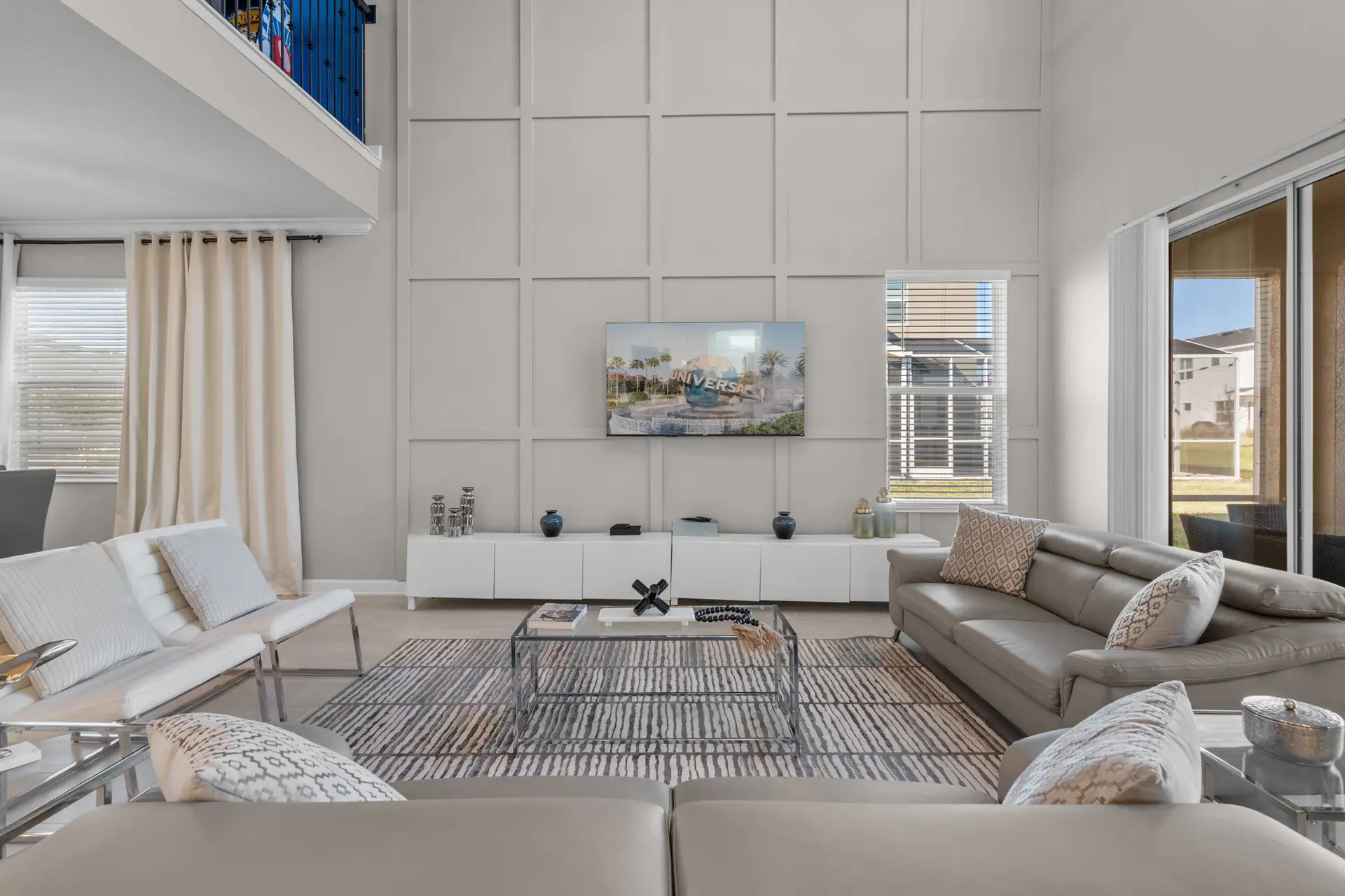 A stylish living room with a sectional sofa, white chairs, and a large TV.