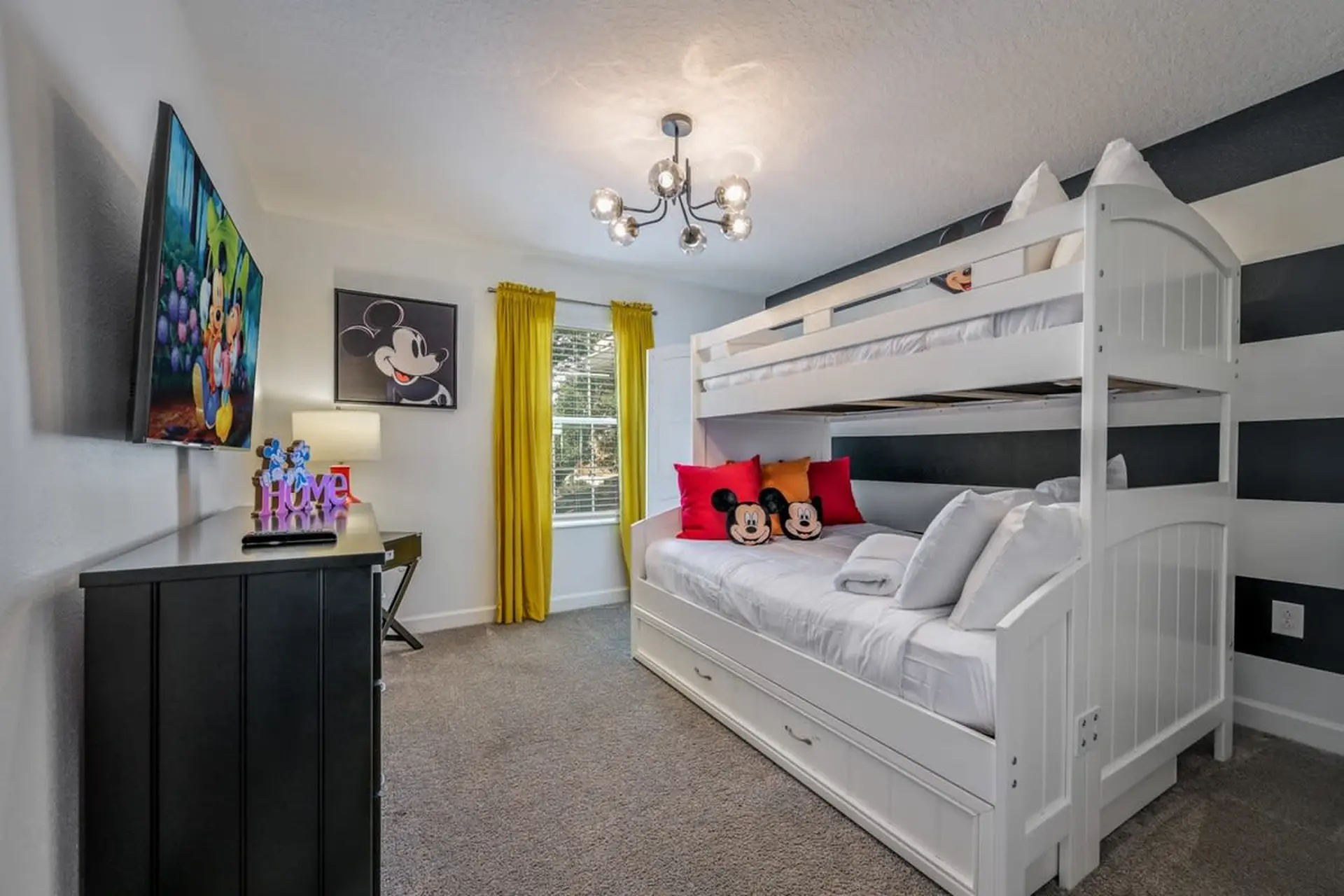 A bunk bed with Mickey Mouse themed pillows and a TV showing a Disney movie.