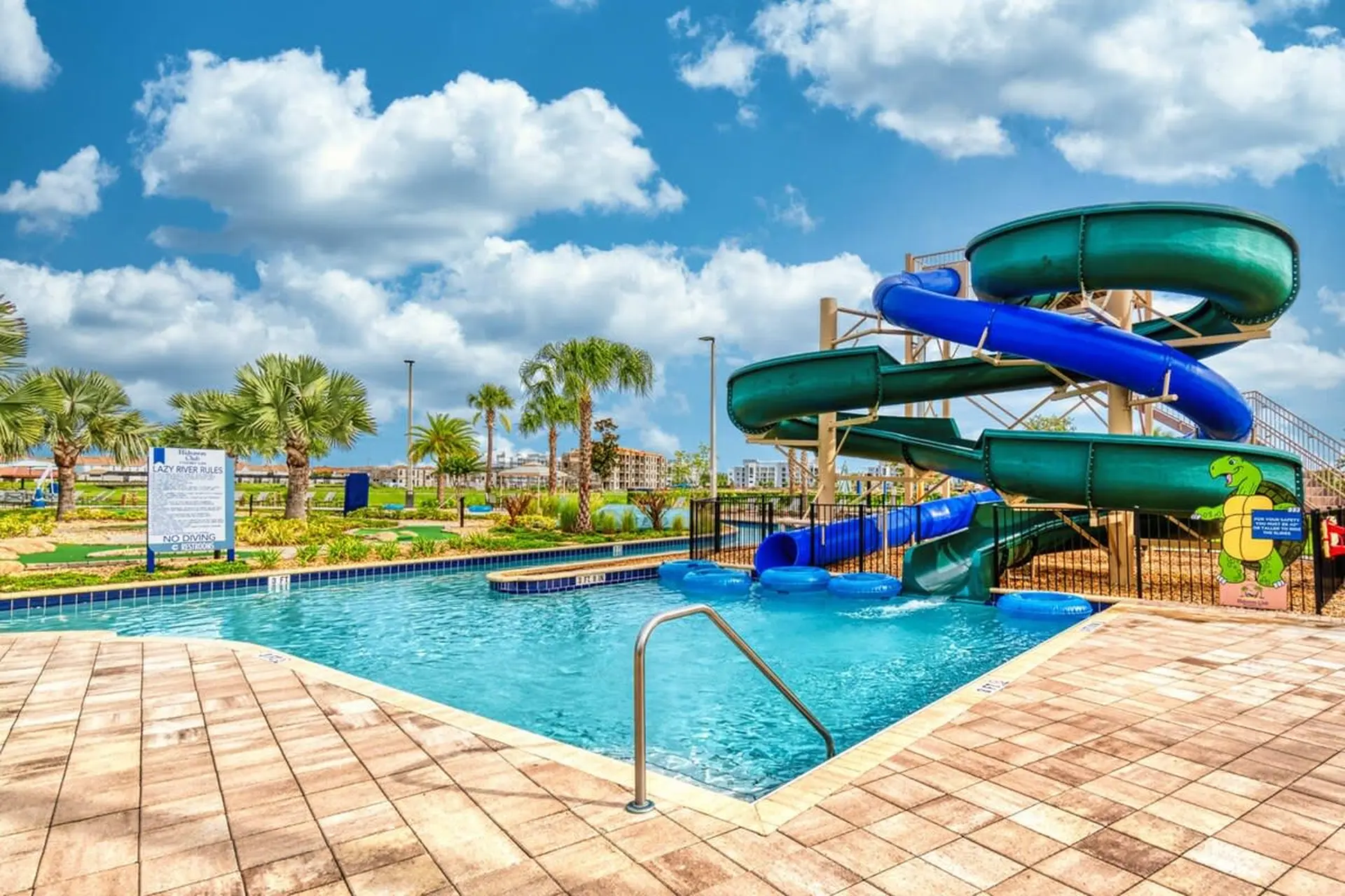 Waterpark with slides and a lazy river on a sunny day with clouds.