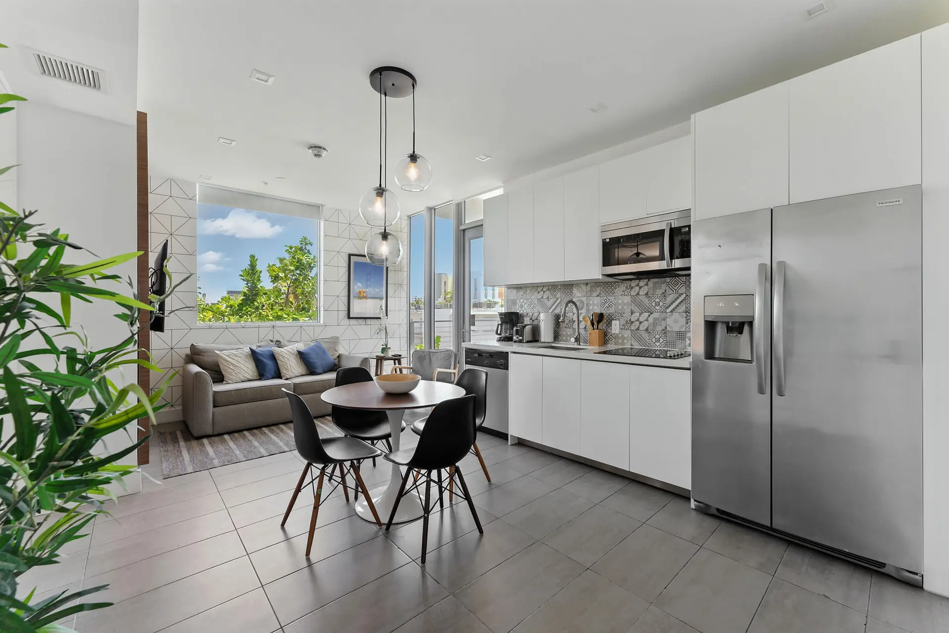 A dining area and kitchen with a sofa and plants.