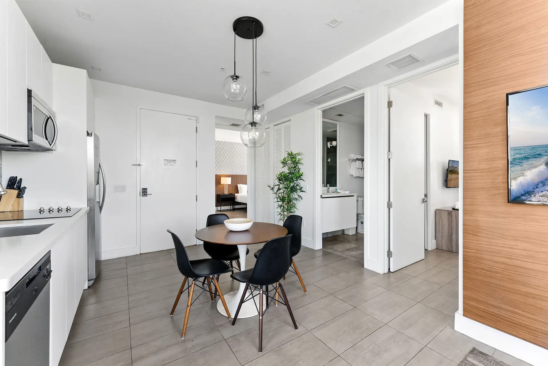 A modern kitchen and dining area with white cabinets, a dining table, and chairs.