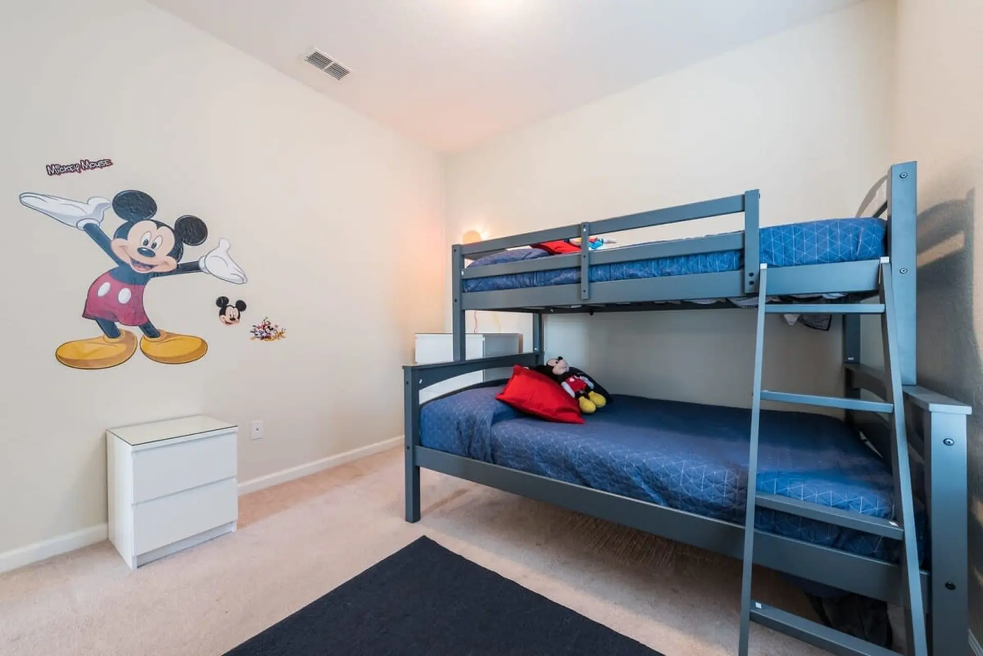 A Disney-themed bedroom with bunk beds and a Mickey Mouse decal.