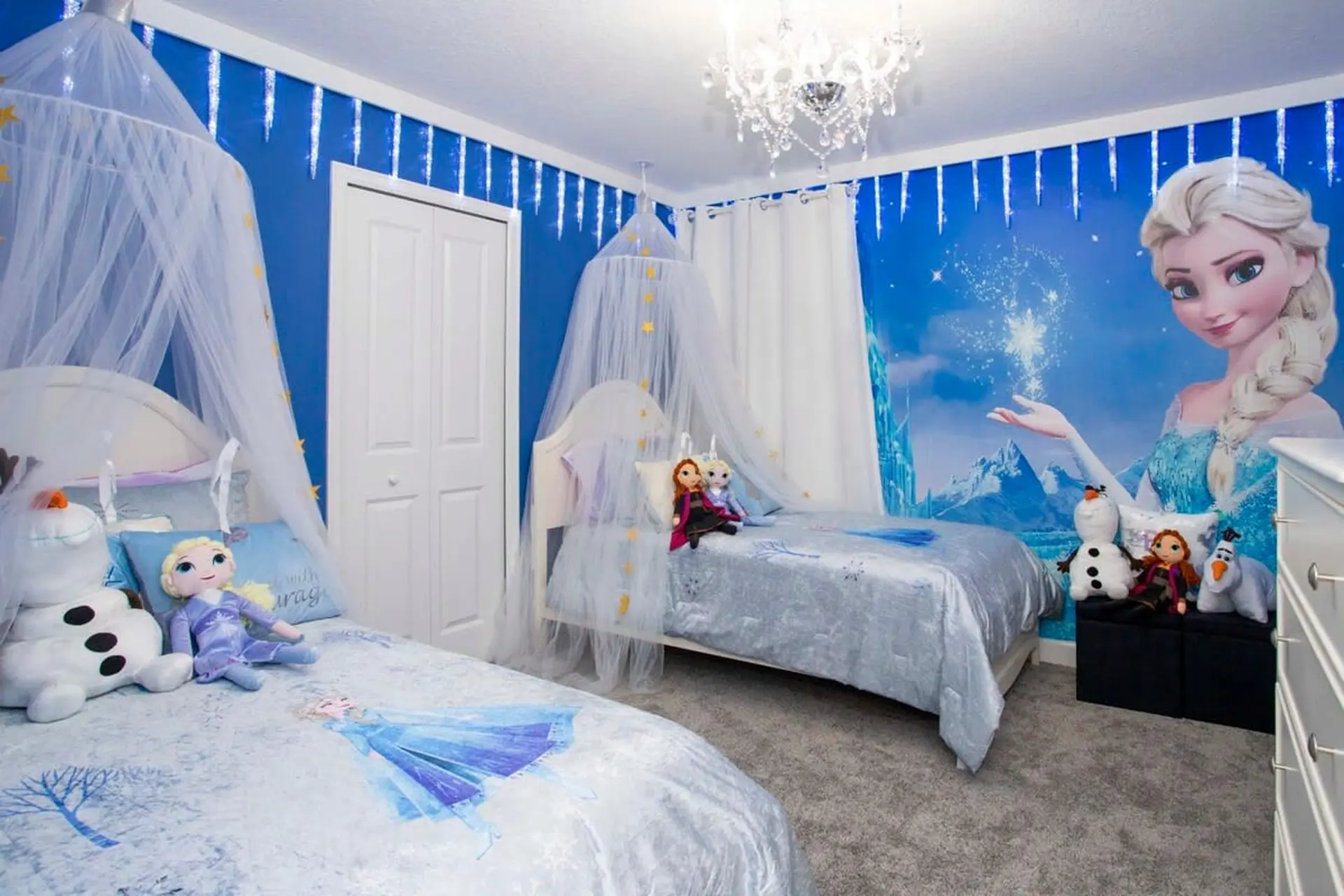 A Frozen-themed bedroom with two beds, Elsa mural, and icicle lights.