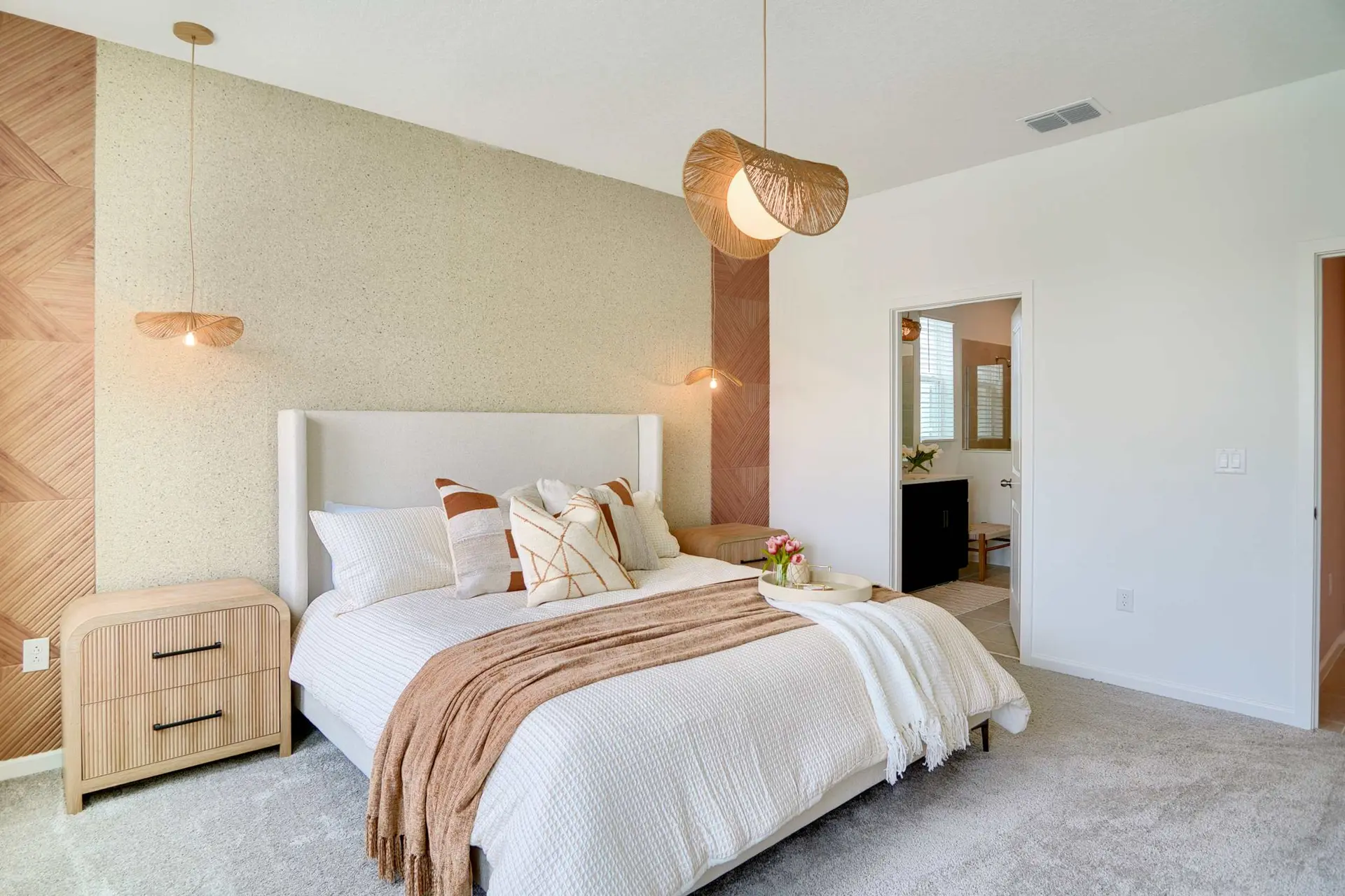 A cozy bedroom with a plush bed, two unique pendant lights, and a textured accent wall.