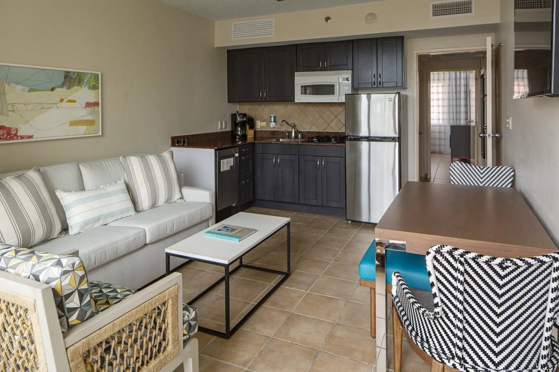 Living room with sofa, coffee table, kitchen, and dining area.