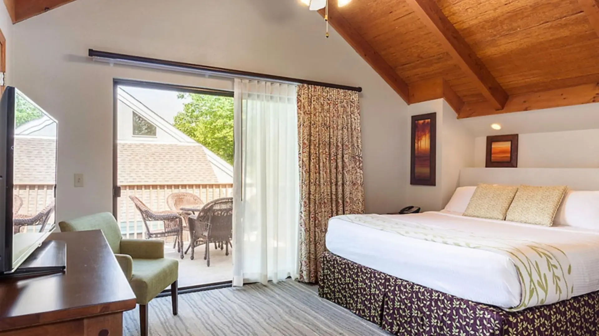 Cozy hotel room with a king-size bed, balcony, and wood-beamed ceiling.