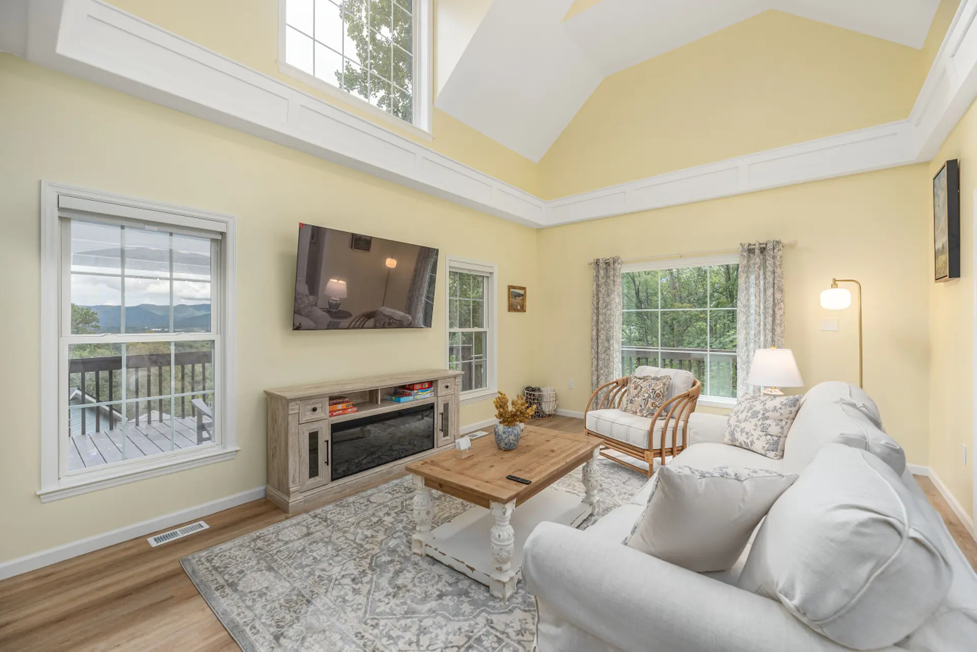 Cozy living room with yellow walls, large windows, and a white sofa.