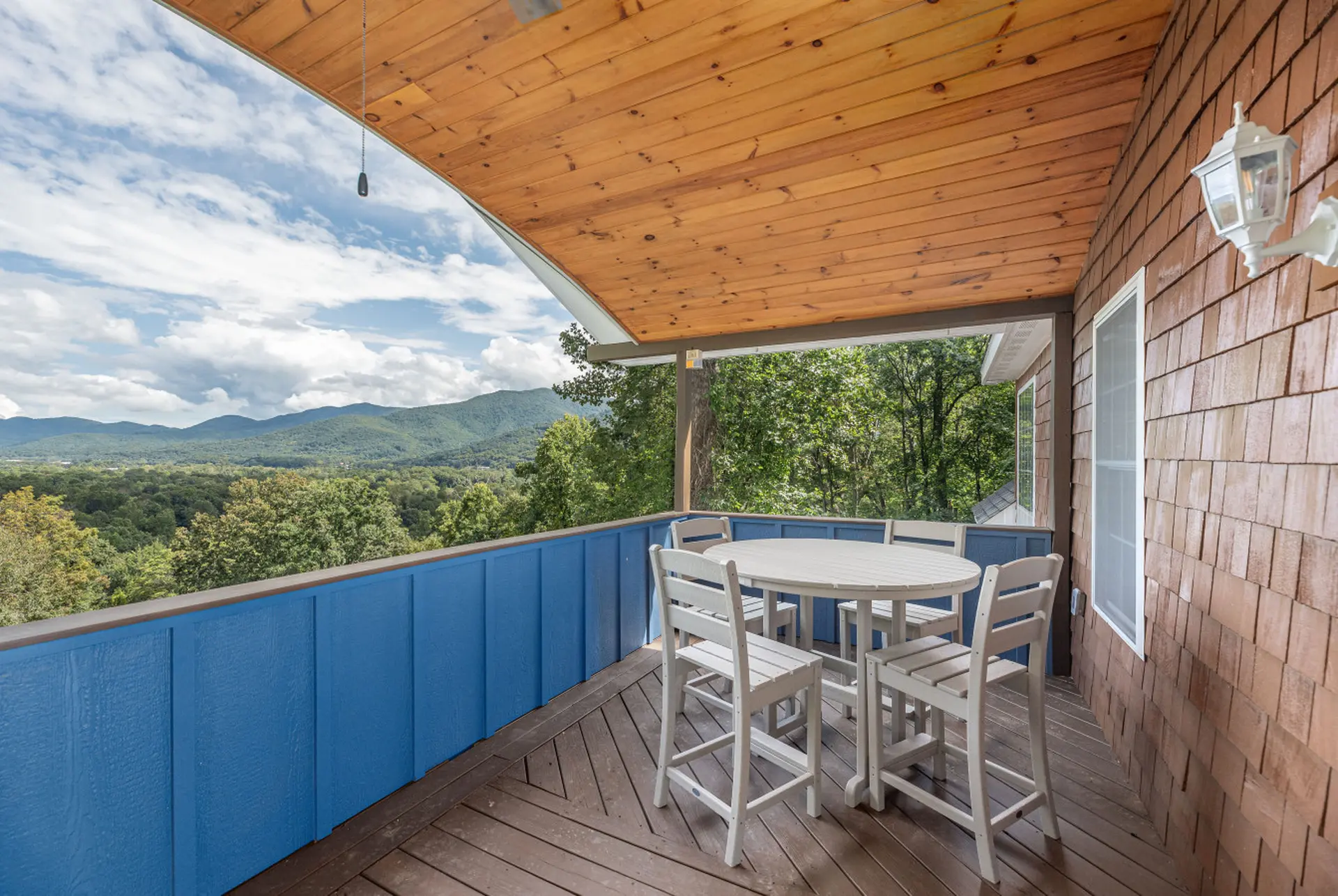 Covered porch with a dining set overlooking a mountain view.