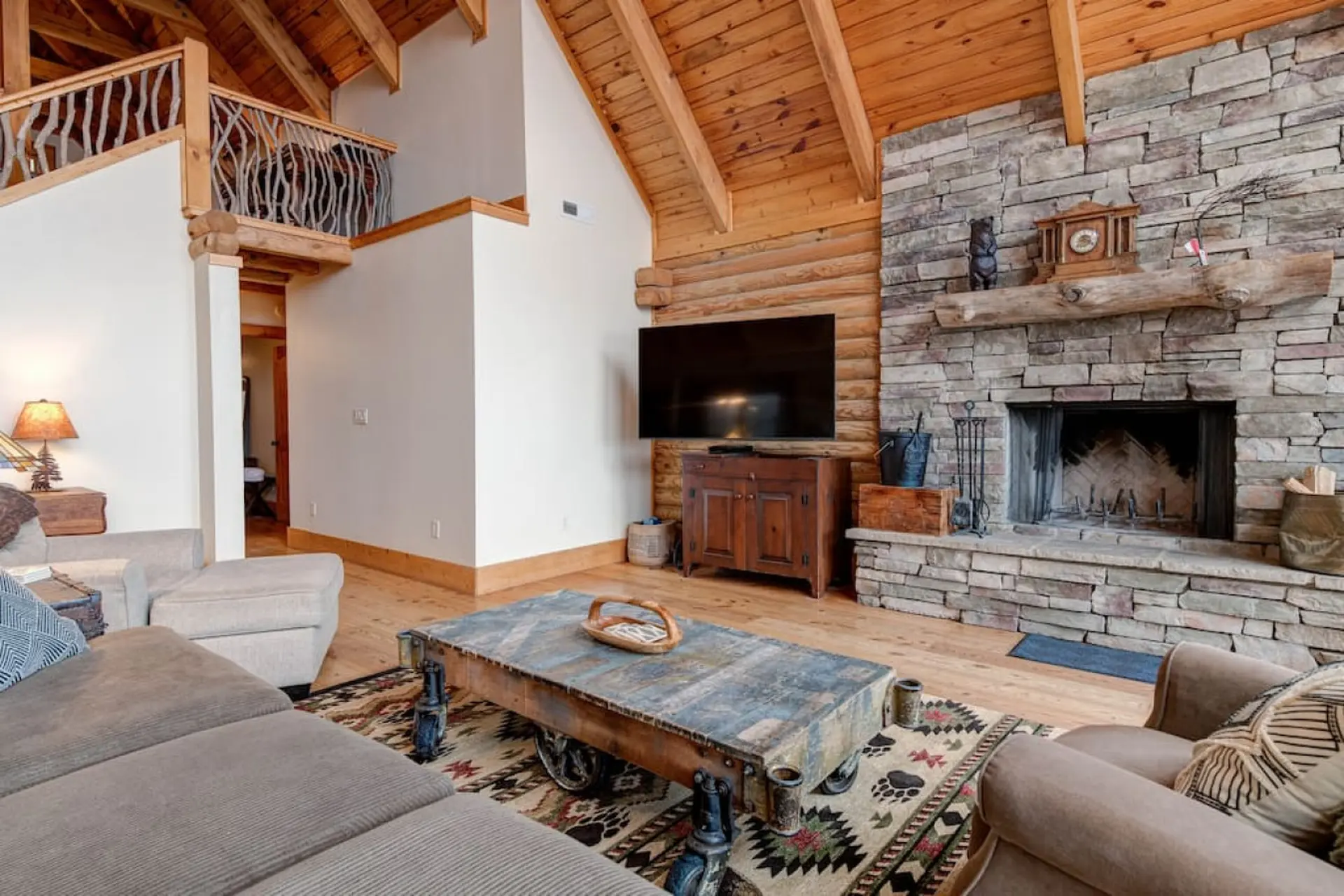 Cozy living room with stone fireplace, TV, sectional sofa, and rustic coffee table.