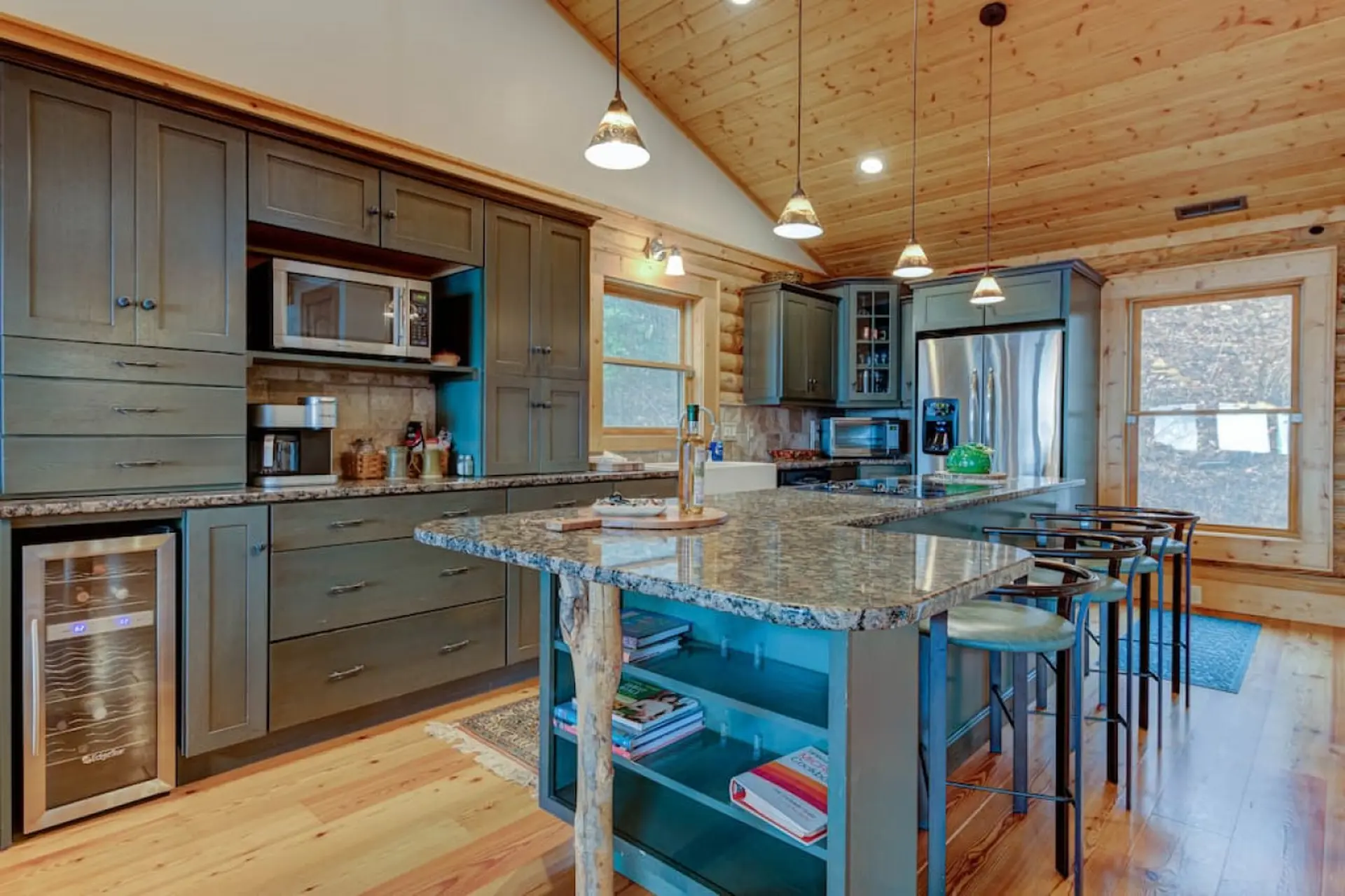 Kitchen with dark gray cabinets, granite island, and wood ceiling.