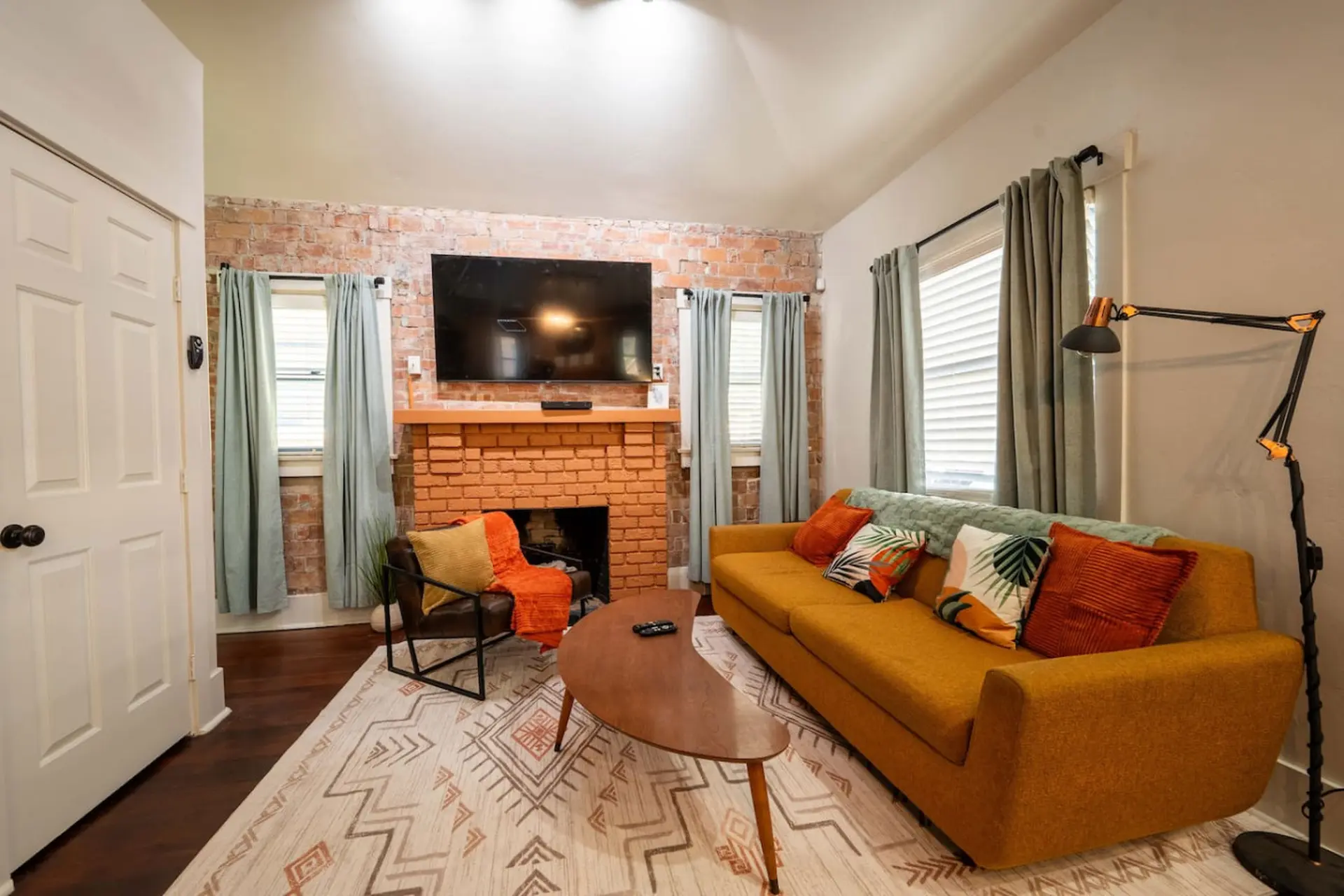 Living room with orange sofa, fireplace, TV, and floor lamp.