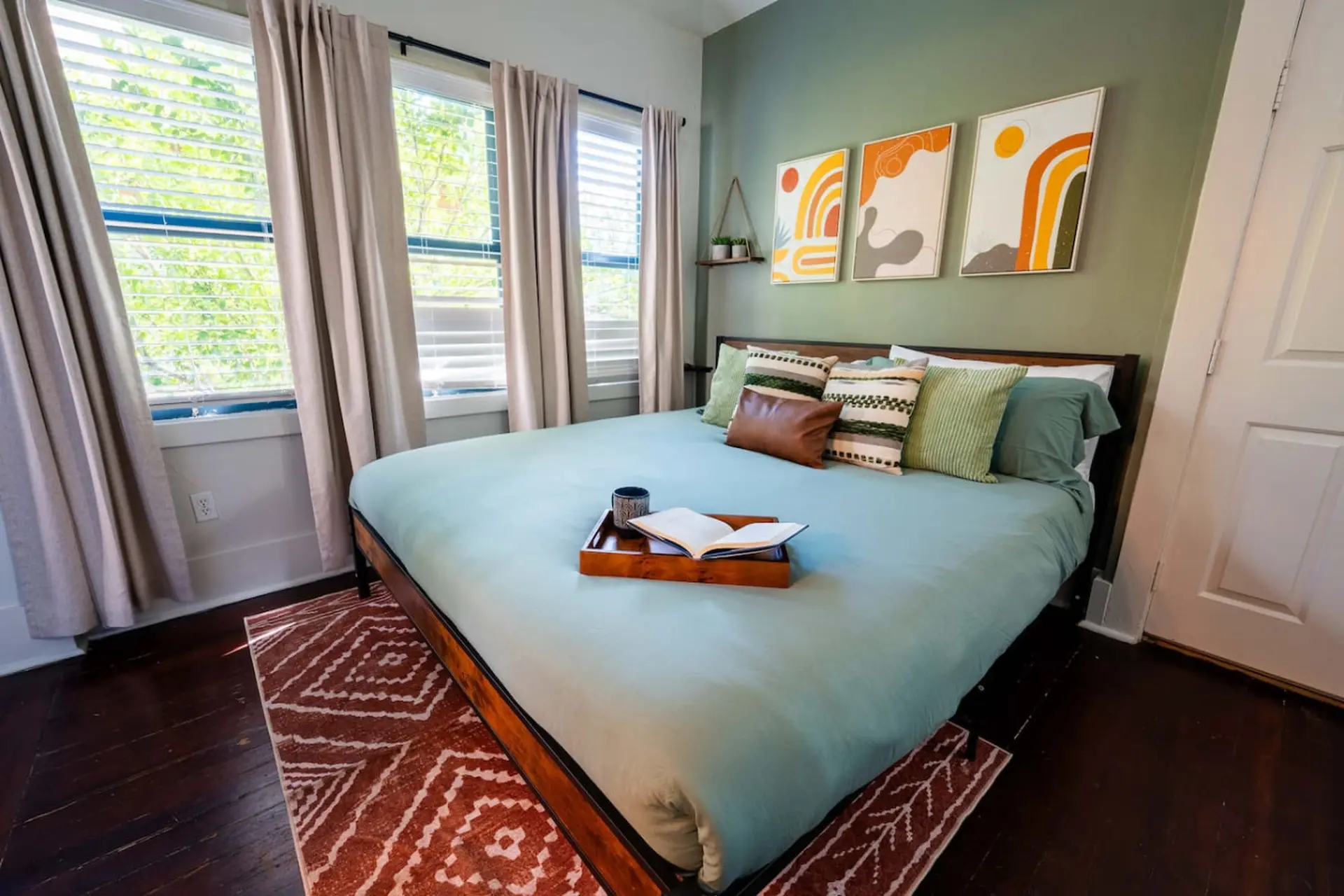 A bedroom with a light blue comforter, wooden bed frame, and decorative pillows.