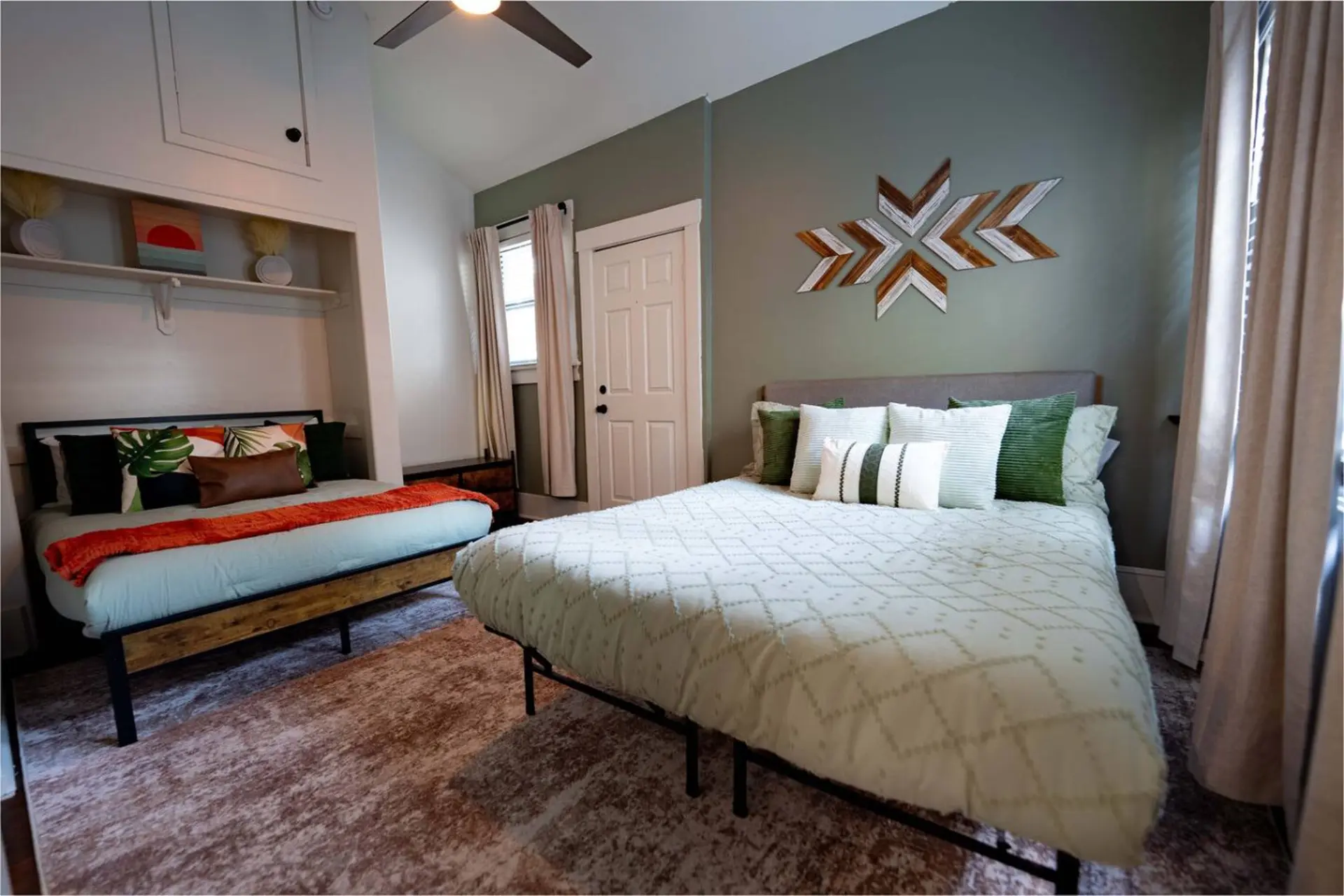 A bedroom with two beds and a geometric wall art.