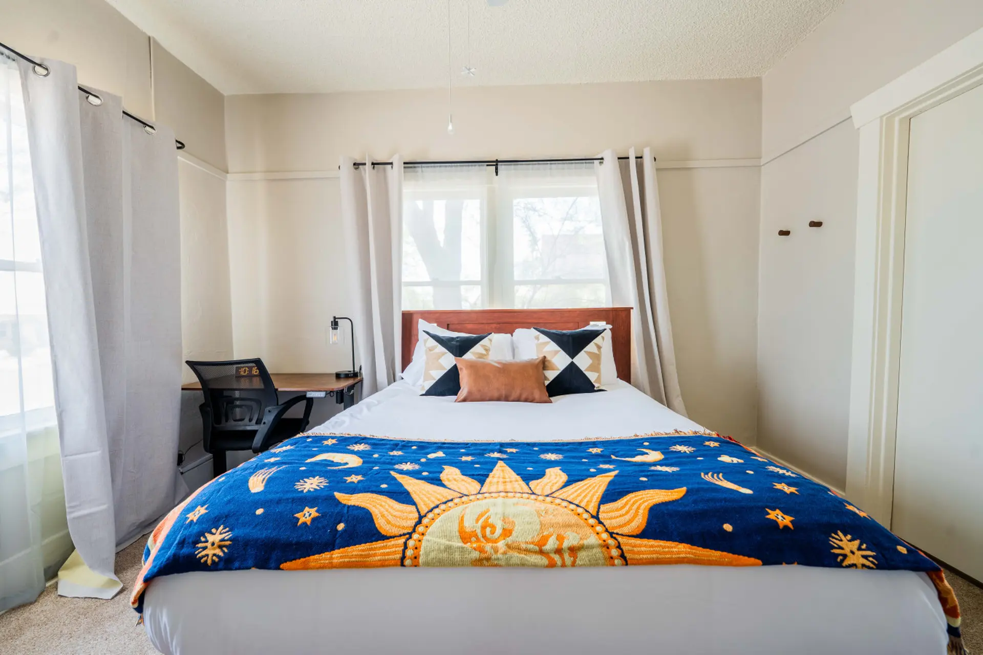 A bed with a blue blanket featuring a sun, moon, and stars.