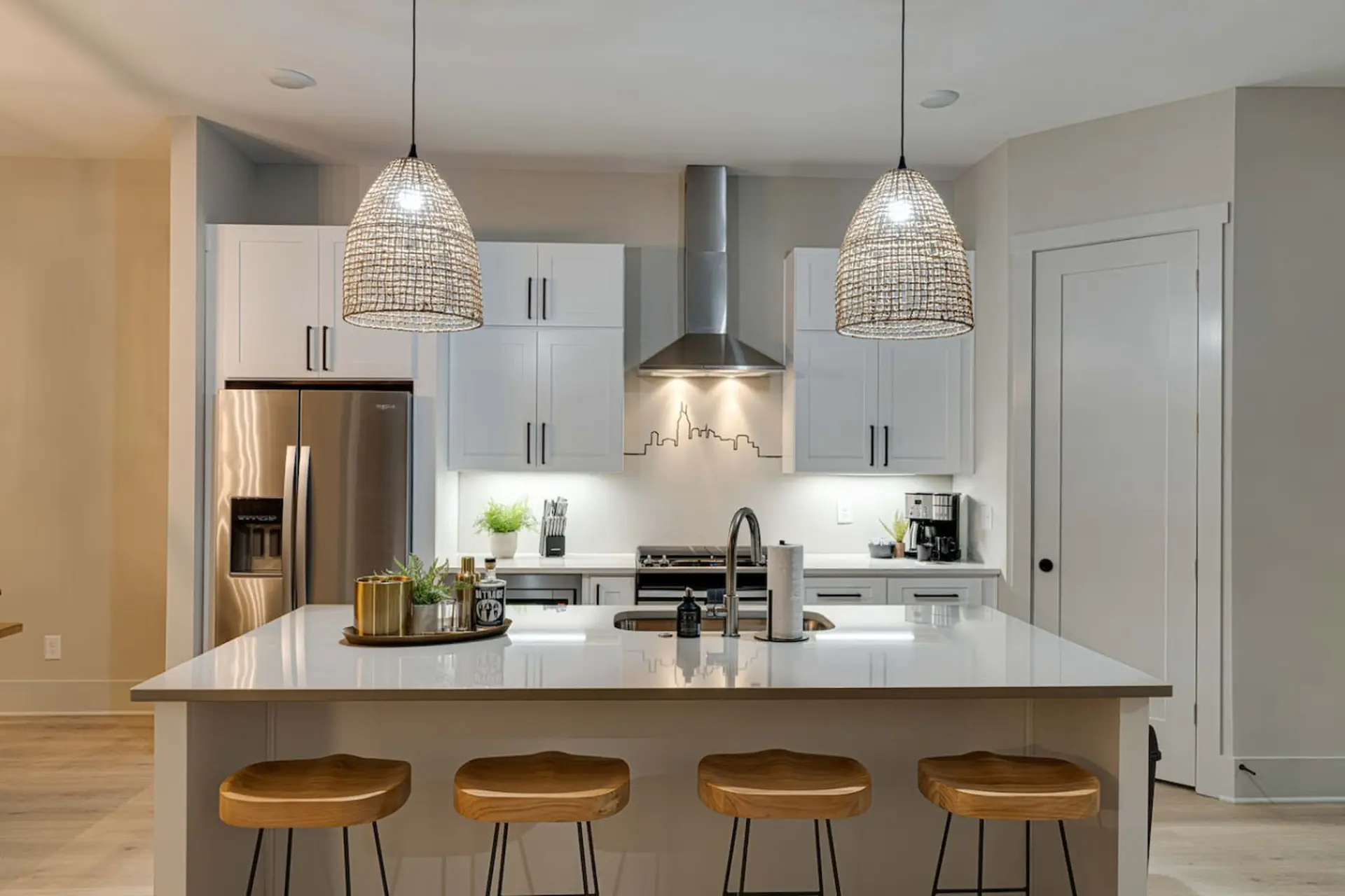 A modern kitchen with white cabinets, stainless steel appliances, and a large island.