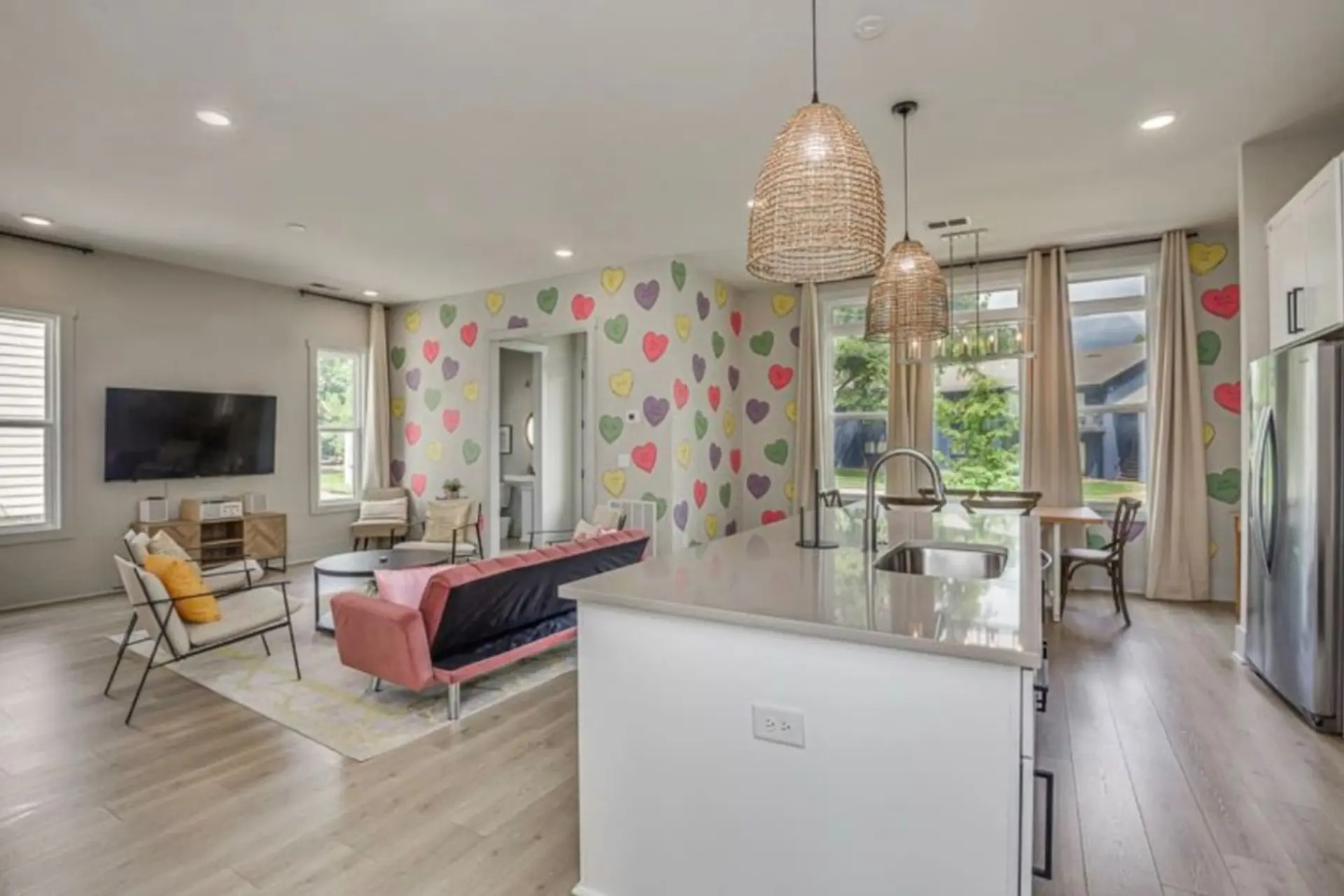 A bright living room and kitchen with a heart-patterned accent wall.