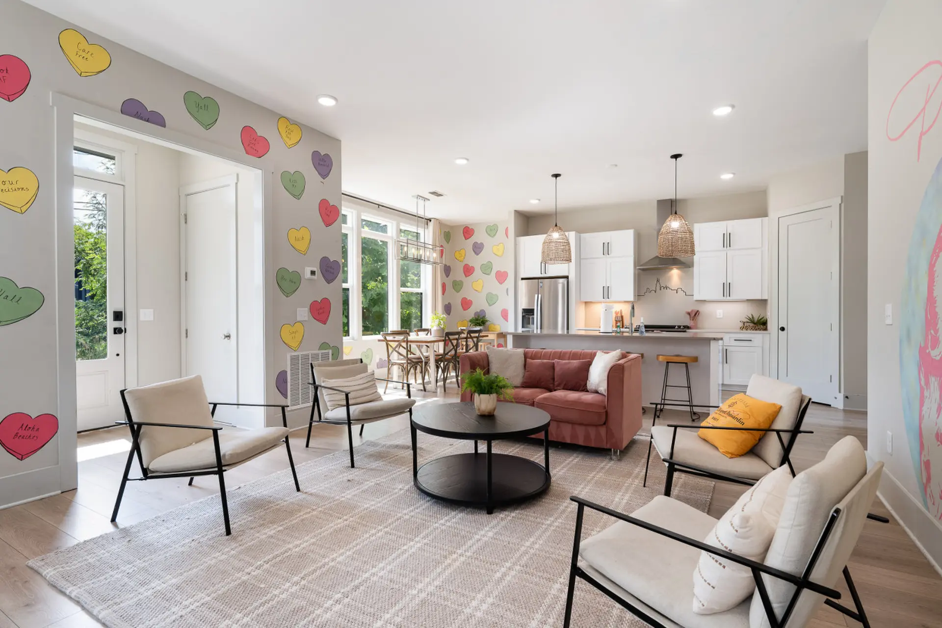 A living room with a pink sofa, armchairs, and heart-shaped decorations on the wall.