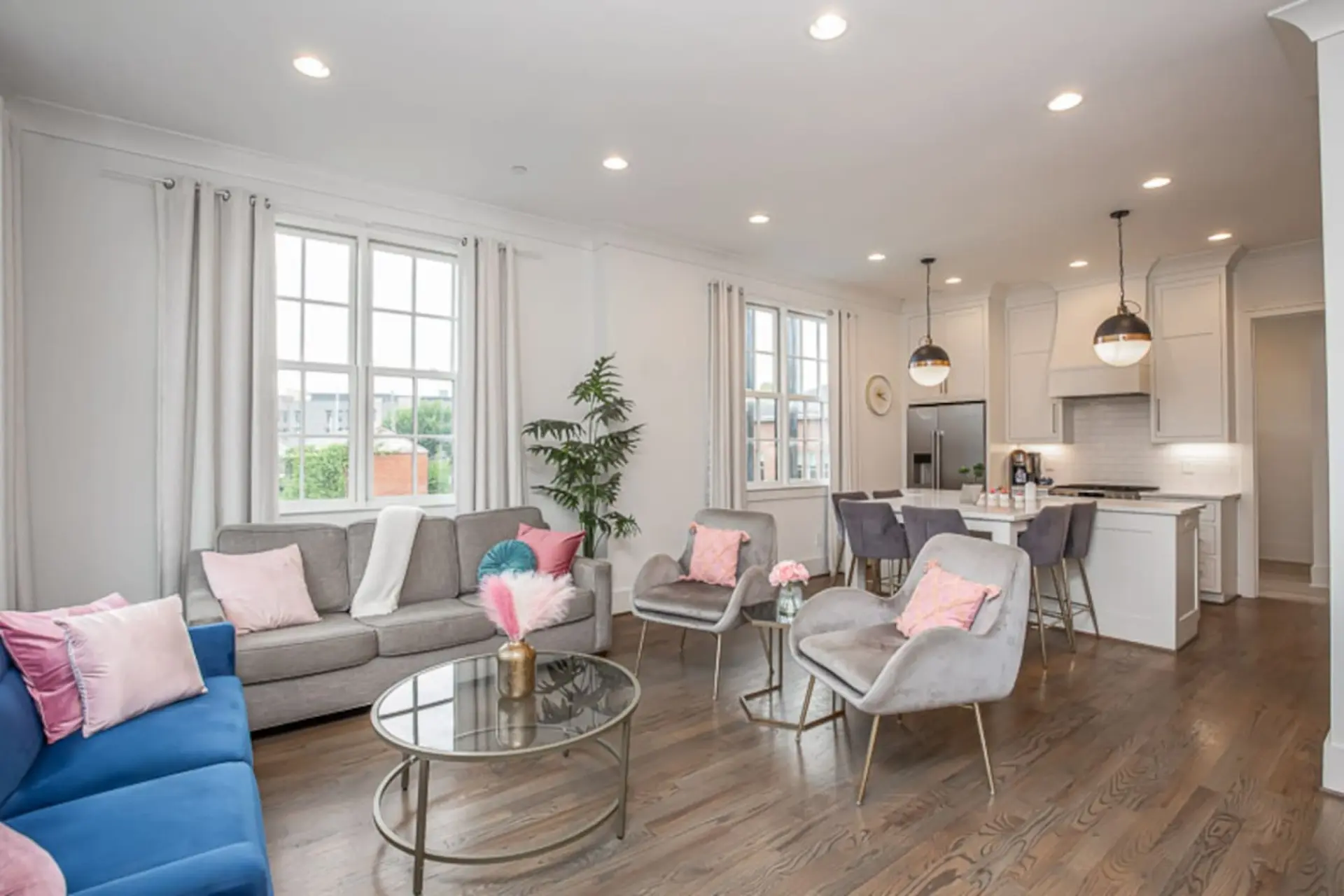 A modern living room and kitchen with a gray sofa, blue sofa, and two accent chairs.