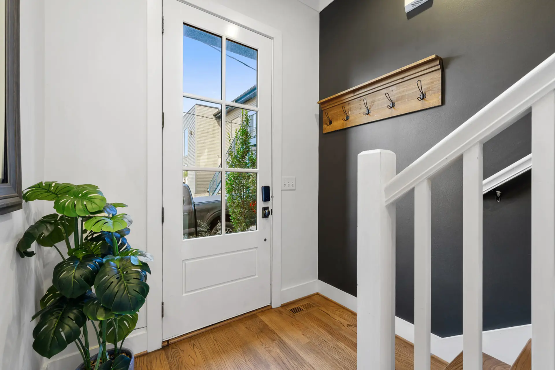 A white door with glass panes and a modern lock is next to a staircase with white railings.