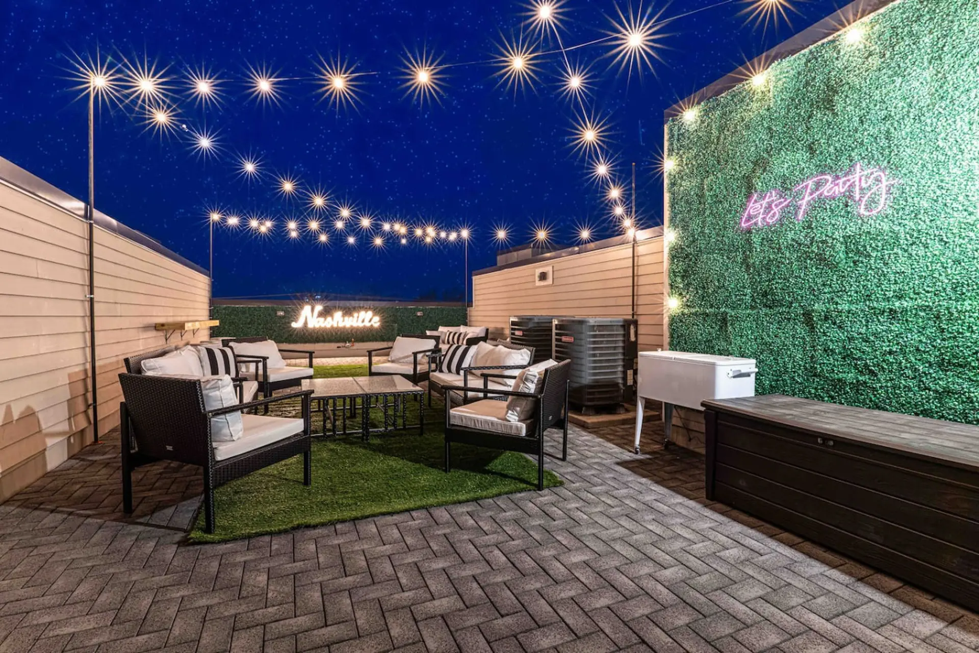 Rooftop patio at night with string lights, lounge seating, and "Nashville" neon sign.
