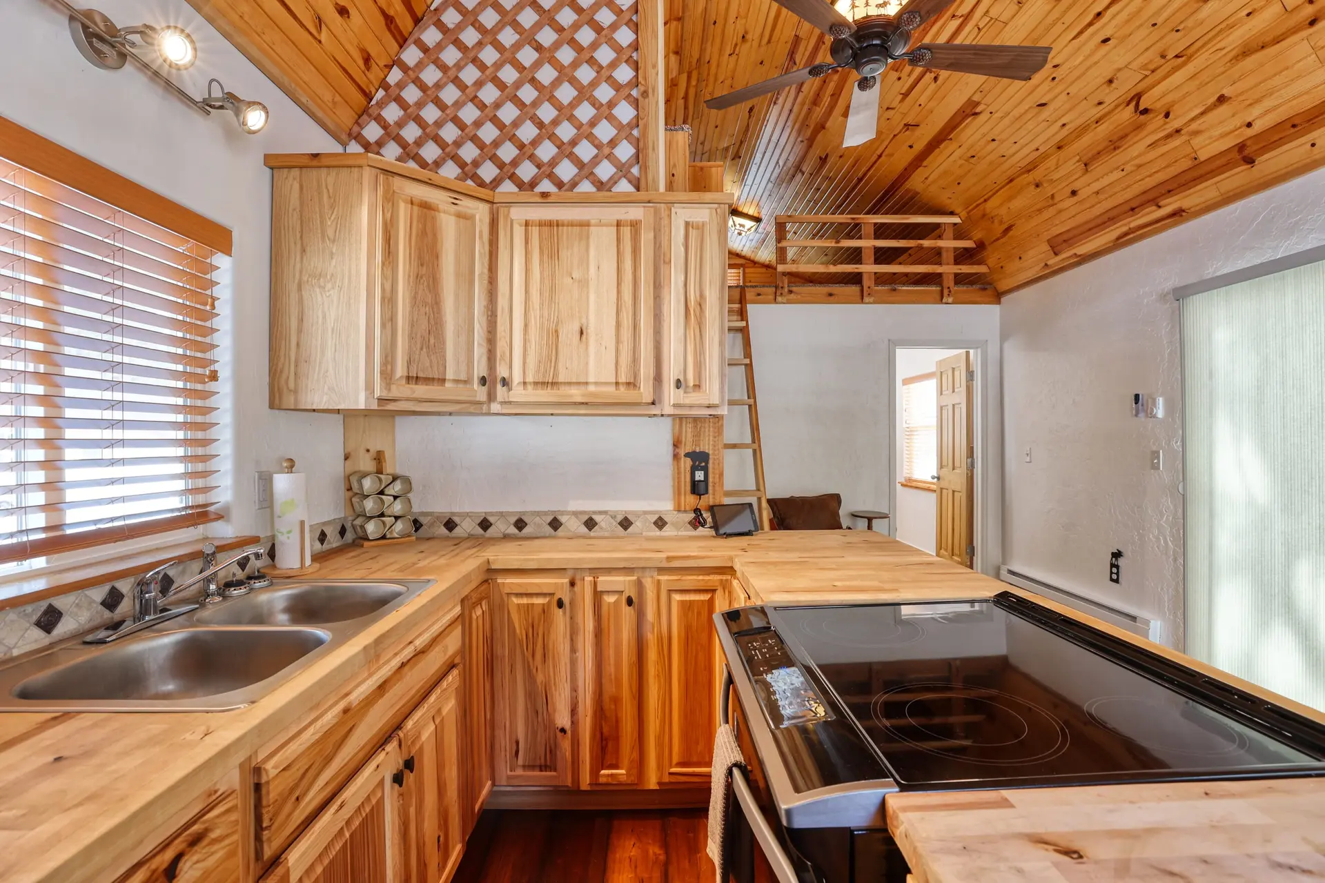 A bright, rustic kitchen with wooden cabinets, countertops, and ceiling.
