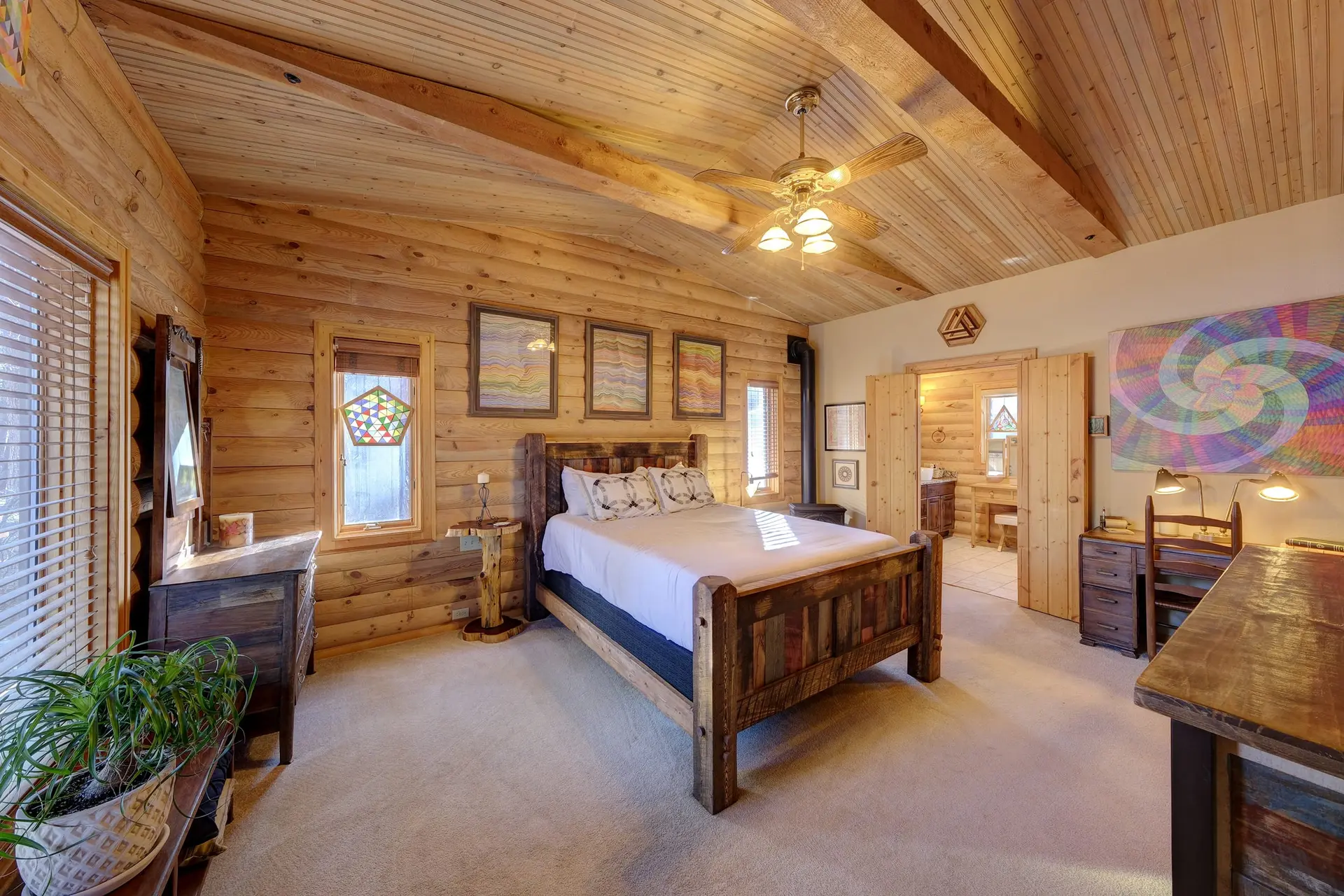 A cozy bedroom with log walls, a wooden bed, and a colorful spiral artwork.