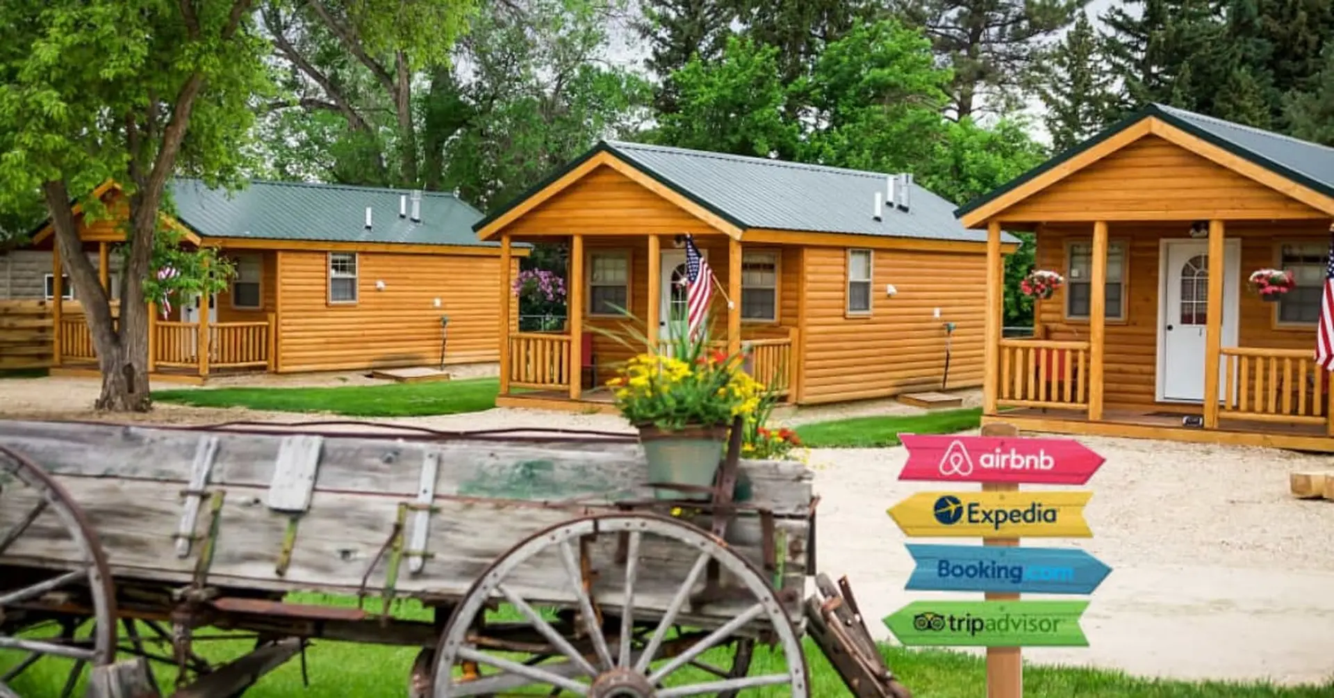 Wooden cabins with a sign pointing to Airbnb, Expedia, Booking.com, and TripAdvisor.