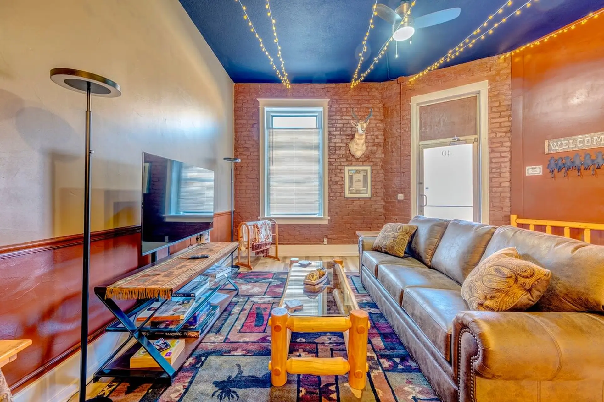 A living room with a leather sofa, television, and rustic decor.