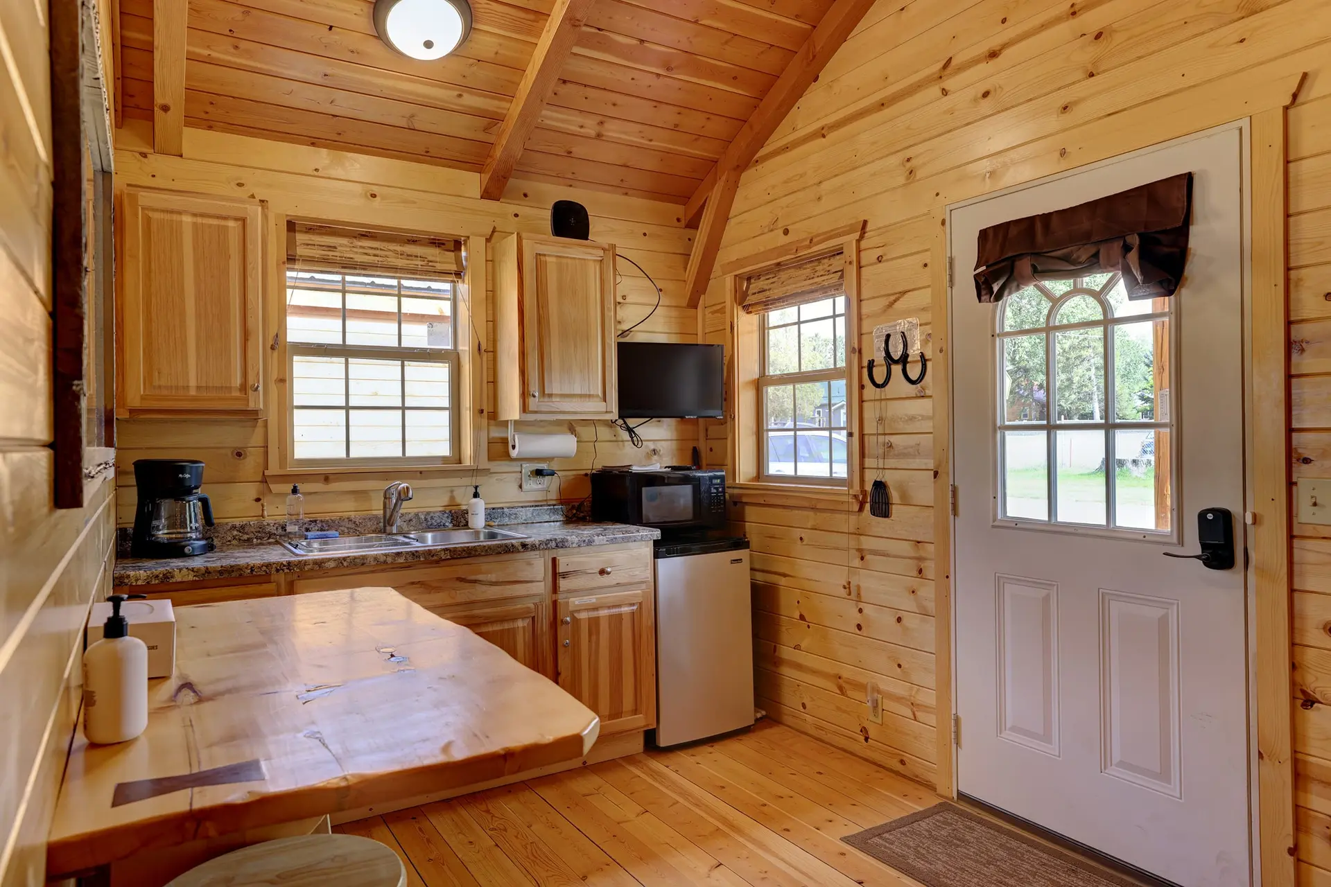 This cozy kitchen features warm wood paneled walls and ceiling, a granite countertop, and a unique l