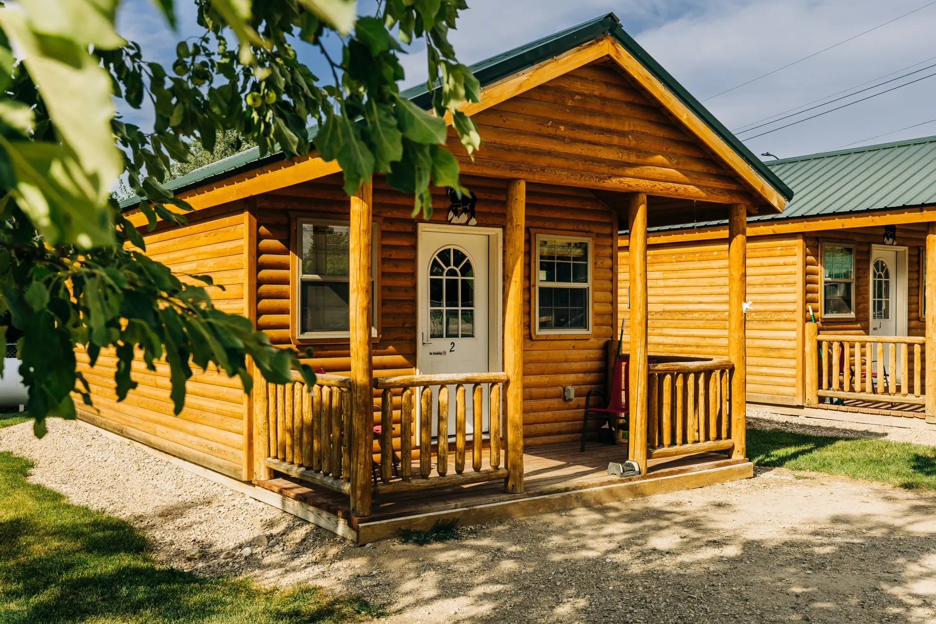 A rustic wooden cabin with a green roof, porch, and railing.