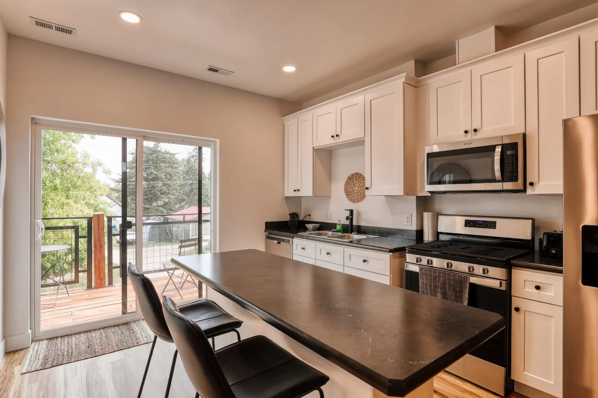 A modern kitchen with a central island, white cabinets, and stainless steel appliances.