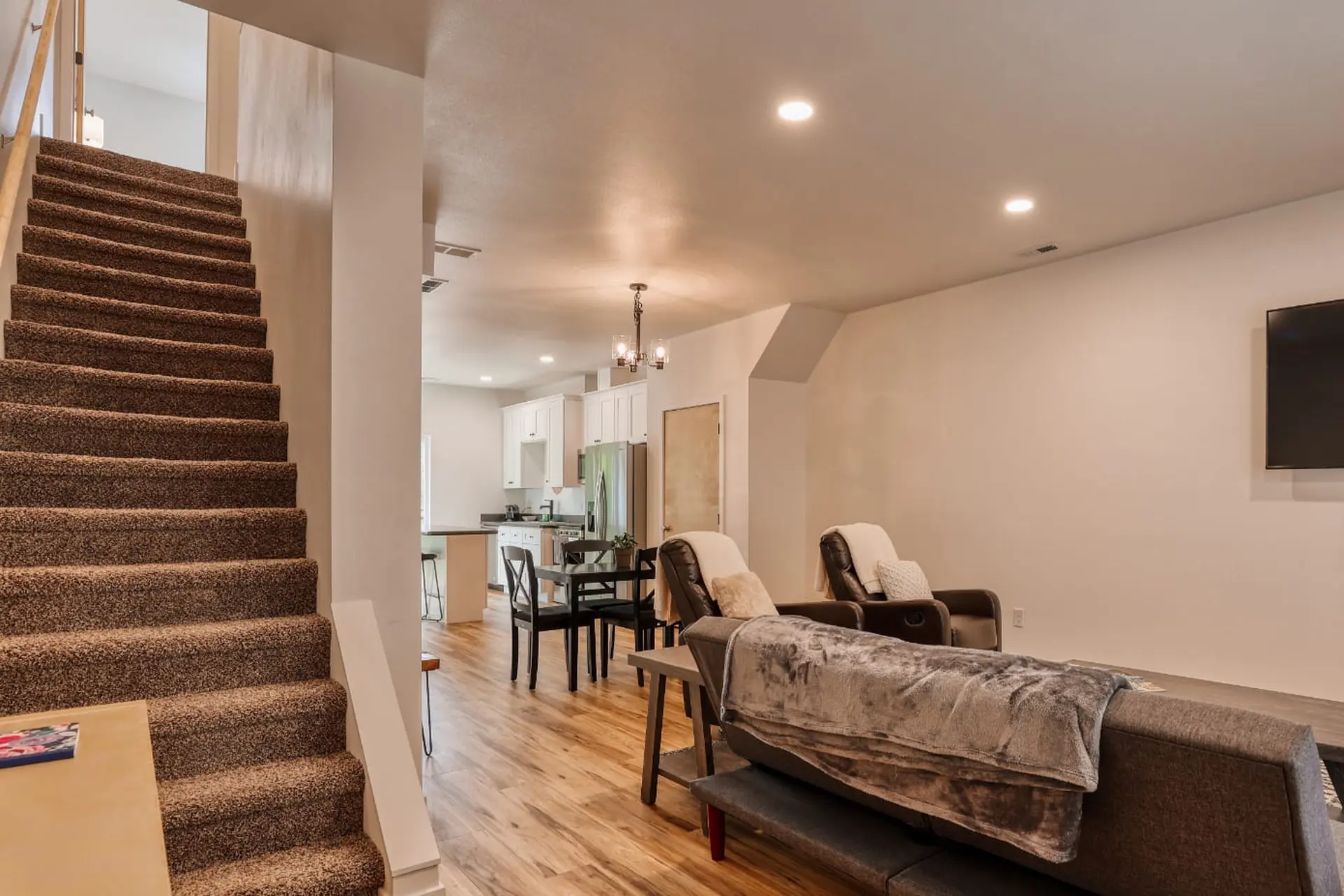 A living room with a TV, couch, two chairs, and a dining area with a table and chairs.