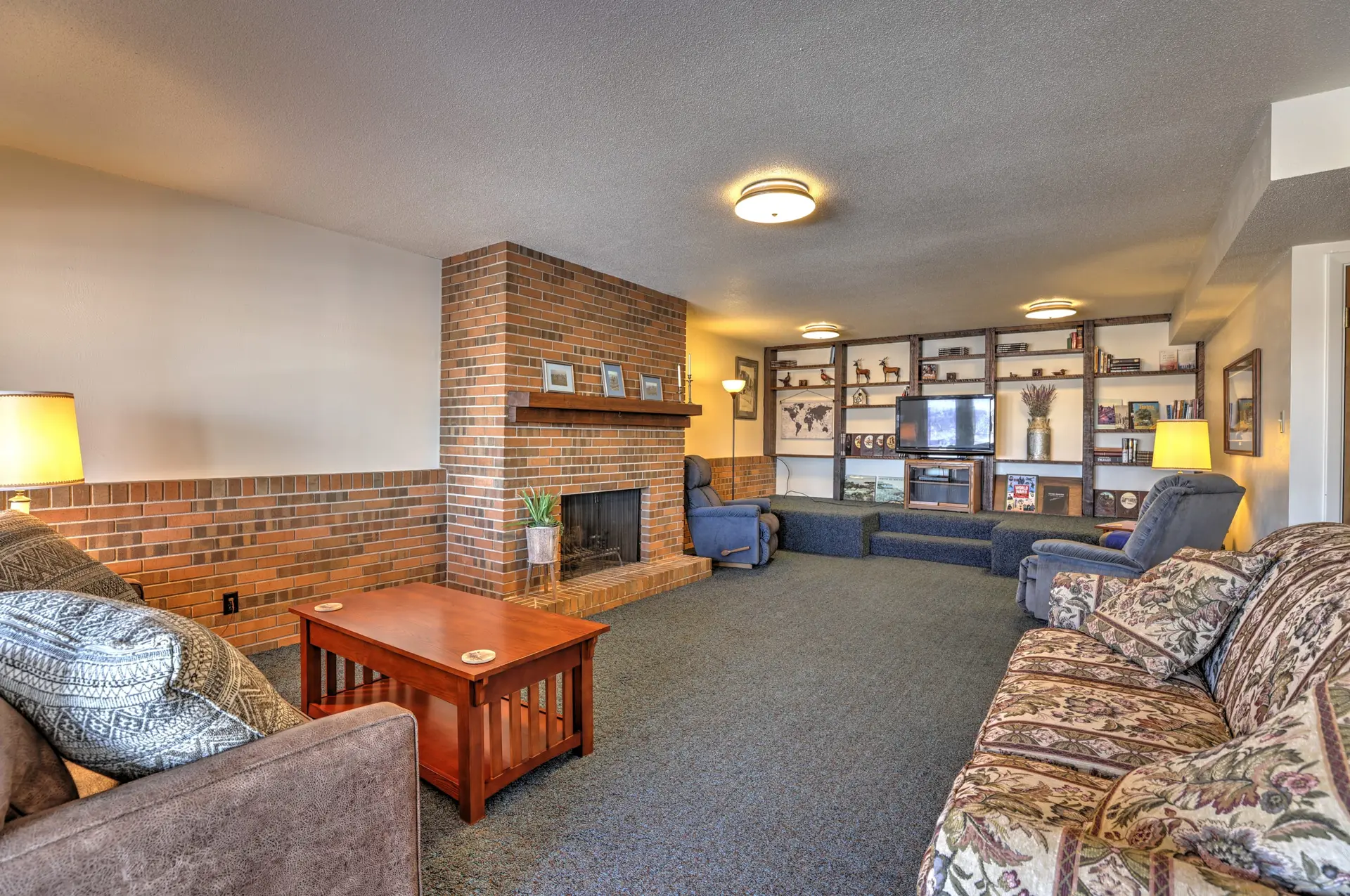 A cozy living room with a brick fireplace, a TV, and comfortable seating.