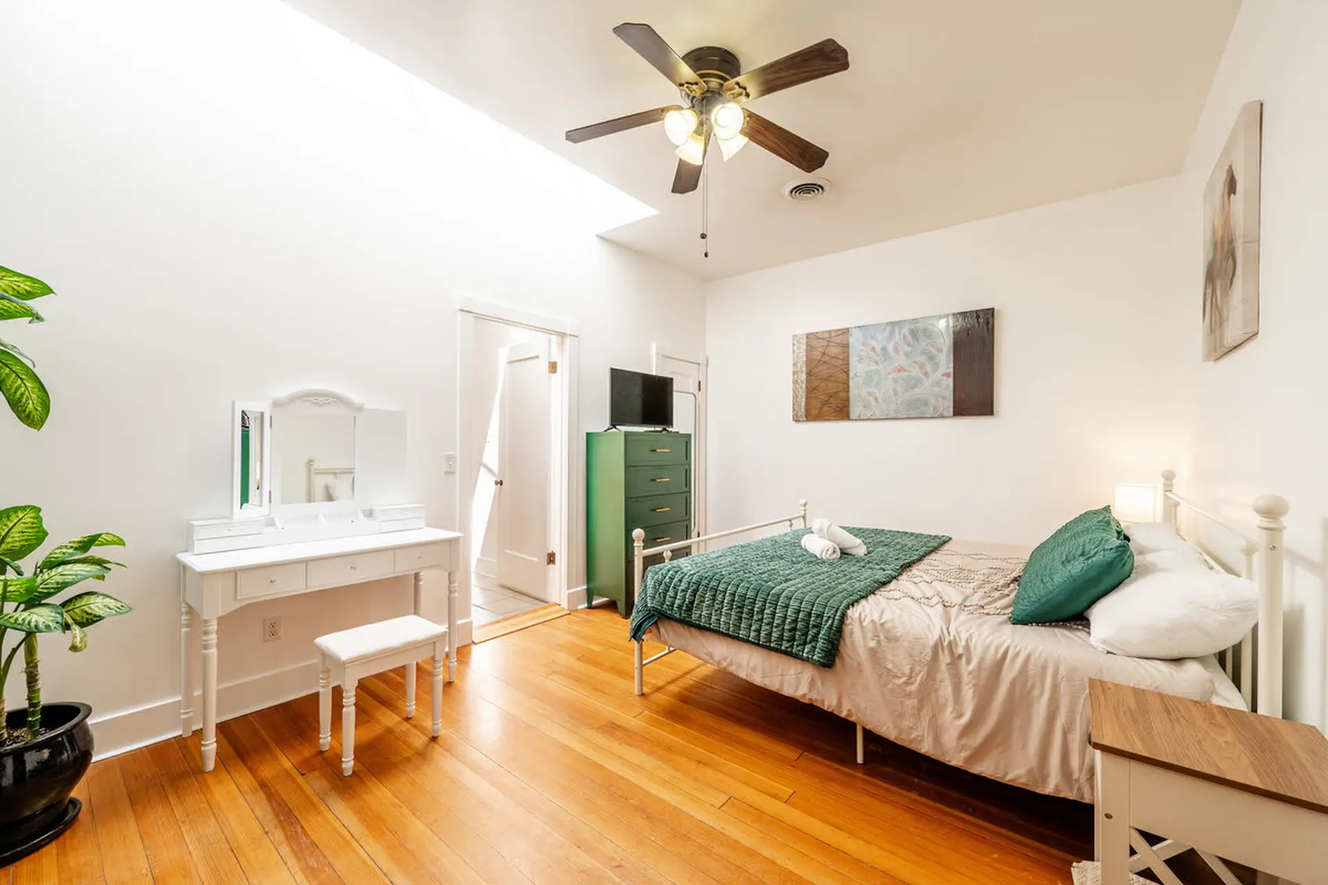 A bright bedroom with a vanity and a bed.