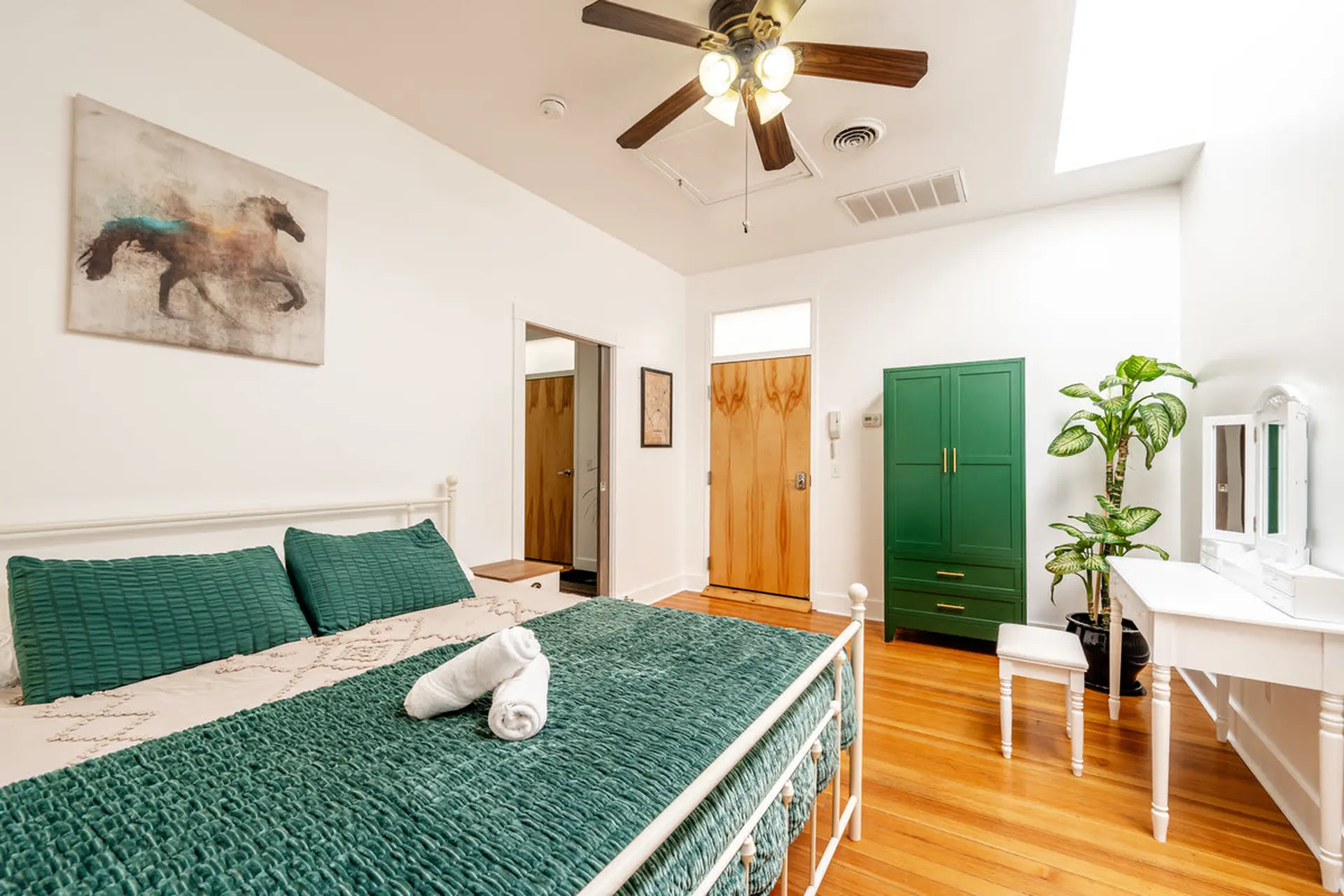 A bedroom with a bed, dresser, and a plant.