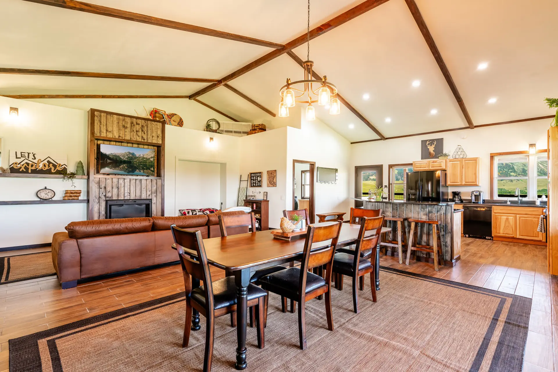 A spacious living and dining area with a sectional couch, fireplace, dining table, and kitchen.