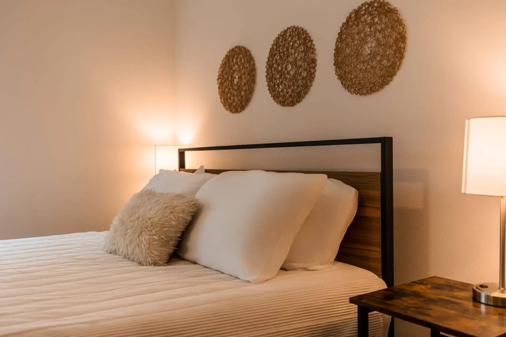 A neatly made bed with white linens, pillows, and a textured accent pillow.