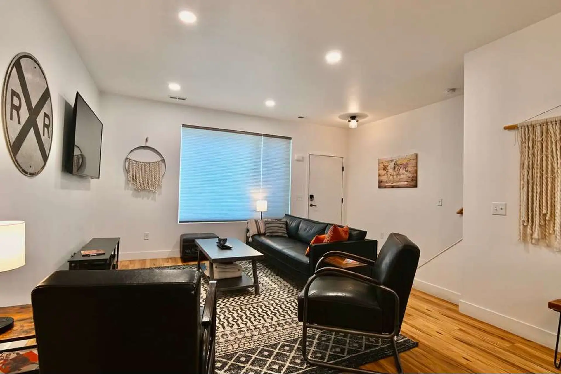 Modern living room with leather furniture, a black and white rug, and decorative wall art.
