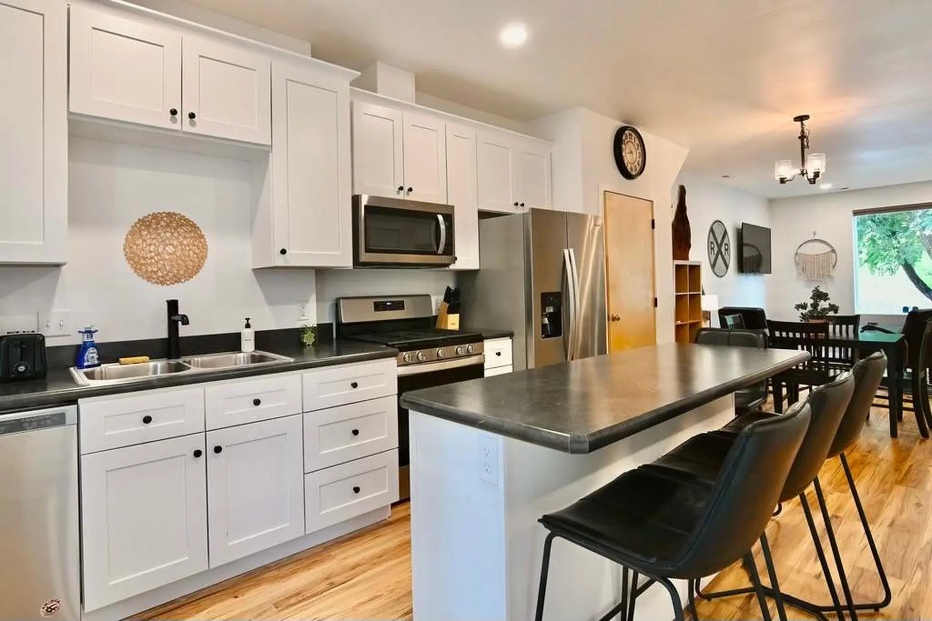 Modern kitchen with white cabinets, stainless steel appliances, and a large island with bar stools.