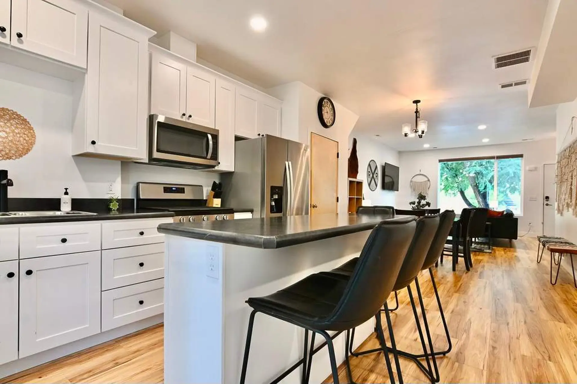 A modern kitchen with white cabinets, stainless steel appliances, and a breakfast bar.