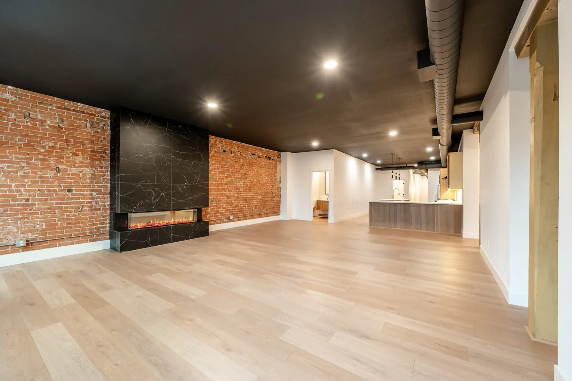A modern living room with a black marble fireplace and exposed brick walls.