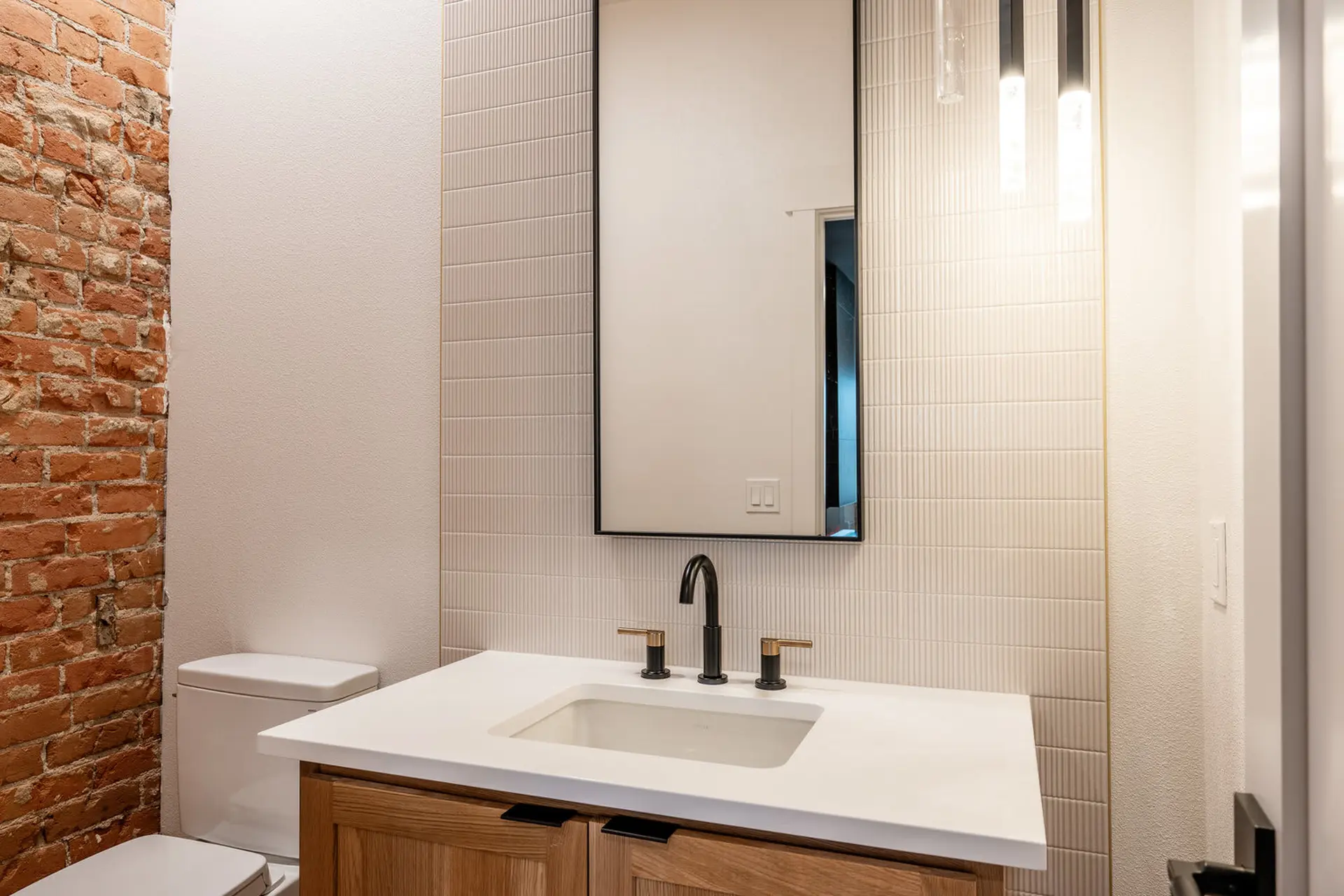 Modern bathroom vanity with wooden cabinets, white countertop, and black fixtures.
