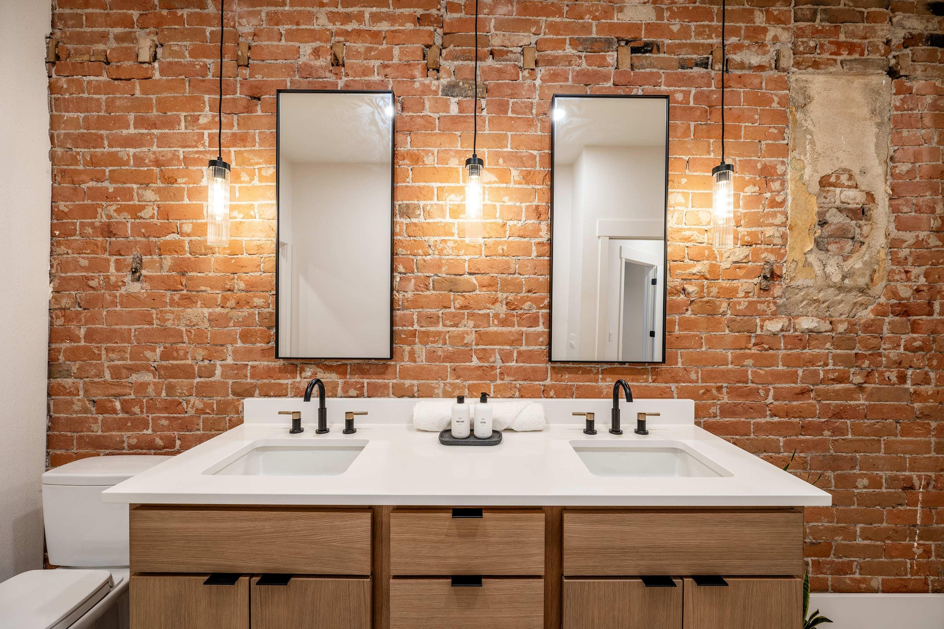 Double vanity against original exposed brick with pendant lighting at The Onyx, The Main Exchange.