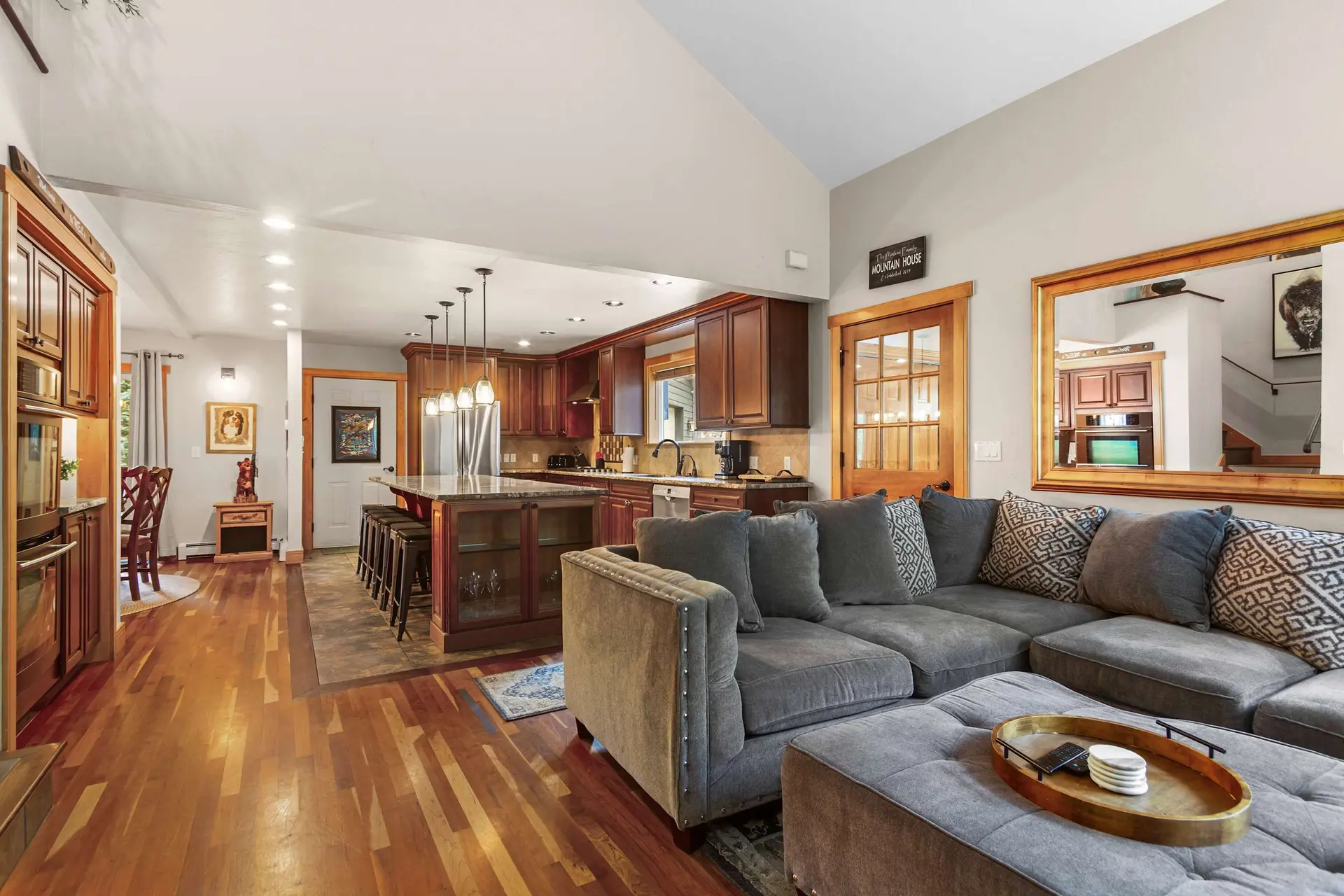 Living room and kitchen with island, seating, and wood floors.